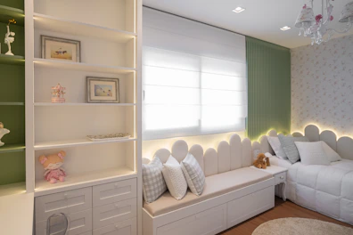 A cozy bedroom with a window seat and shelves.