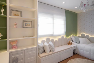 A cozy bedroom with a window seat and shelves.