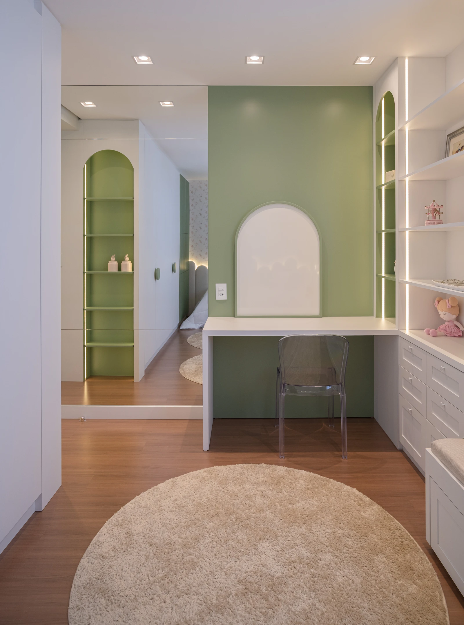 A room with a desk, shelves and a round rug