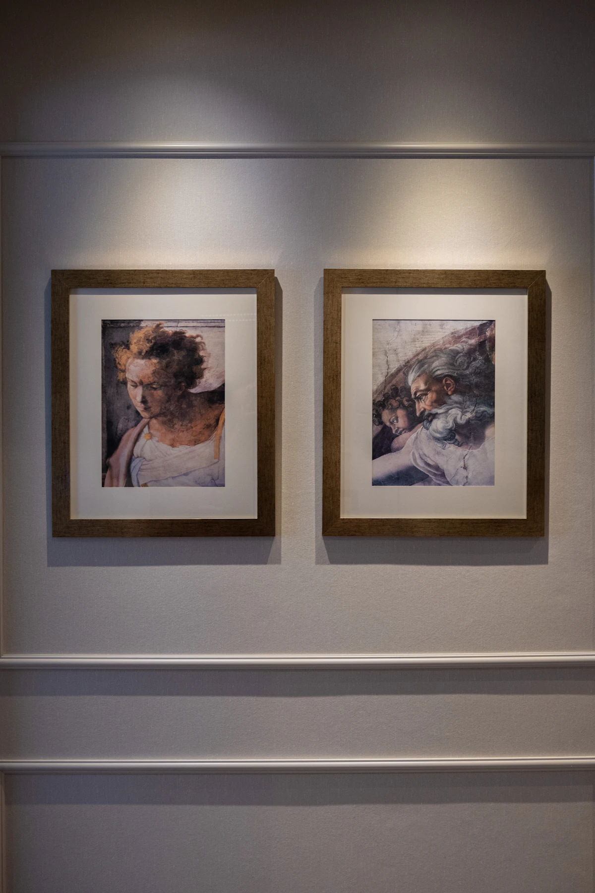 Two framed classical portrait studies hung on a panelled gallery wall