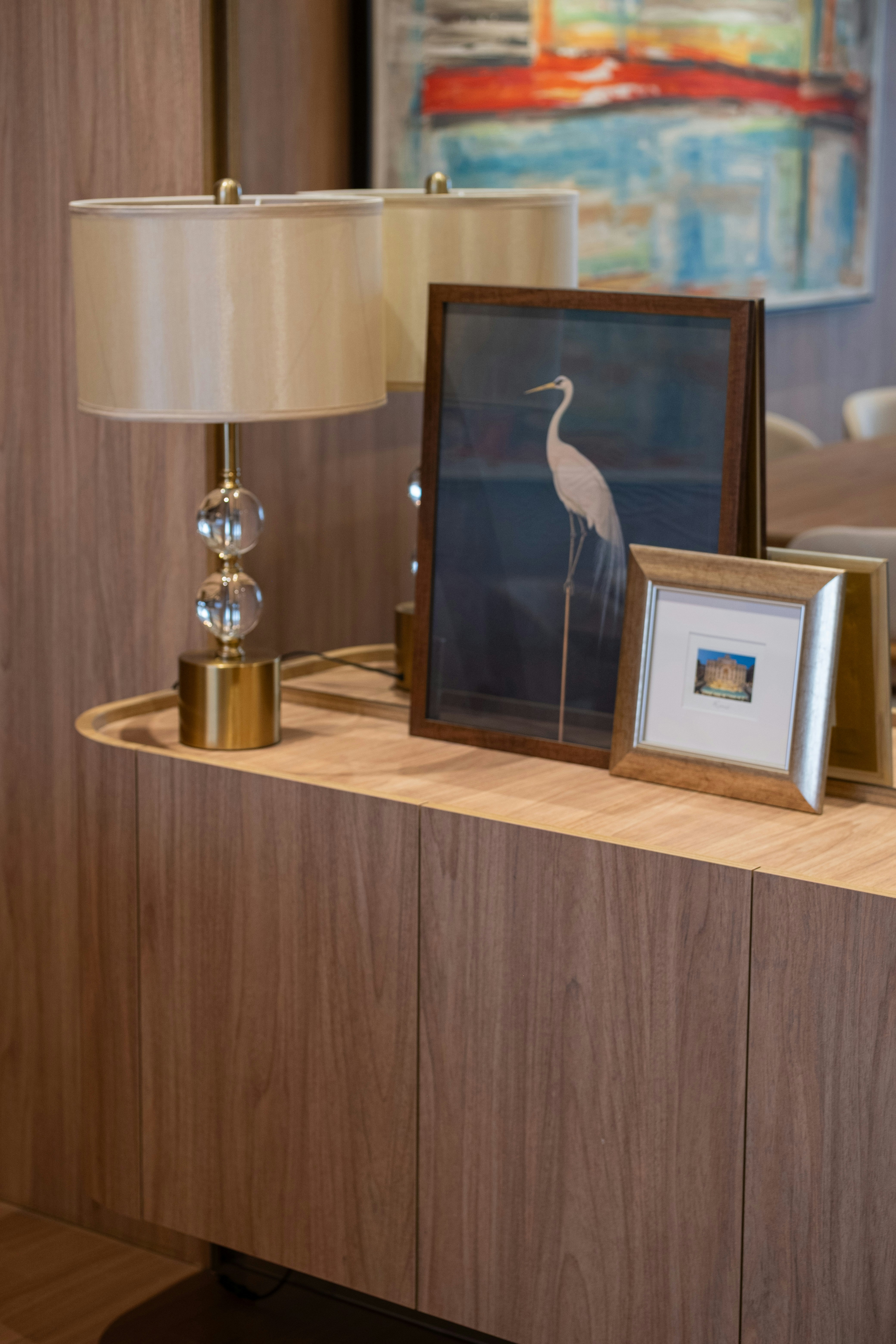 A lamp and framed artwork on a wooden console table.