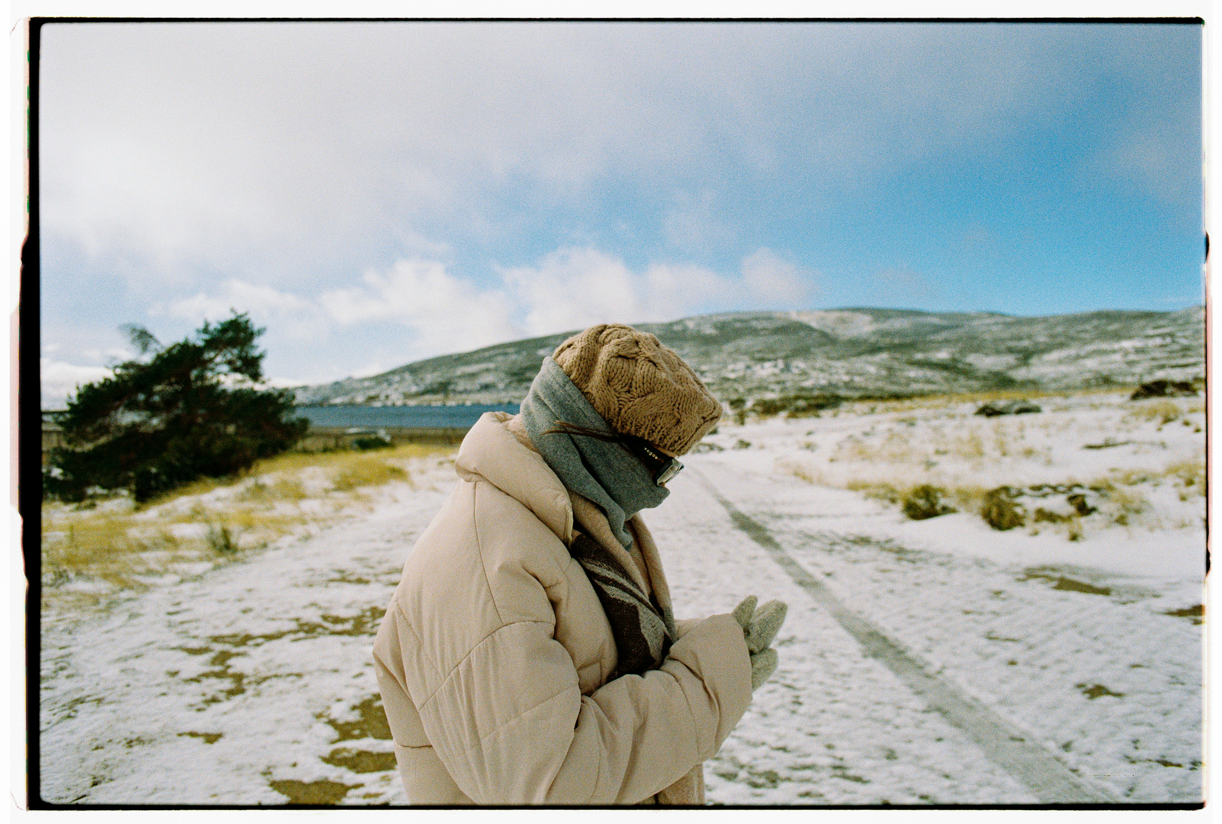 Person in winter clothing looking at phone on snowy path