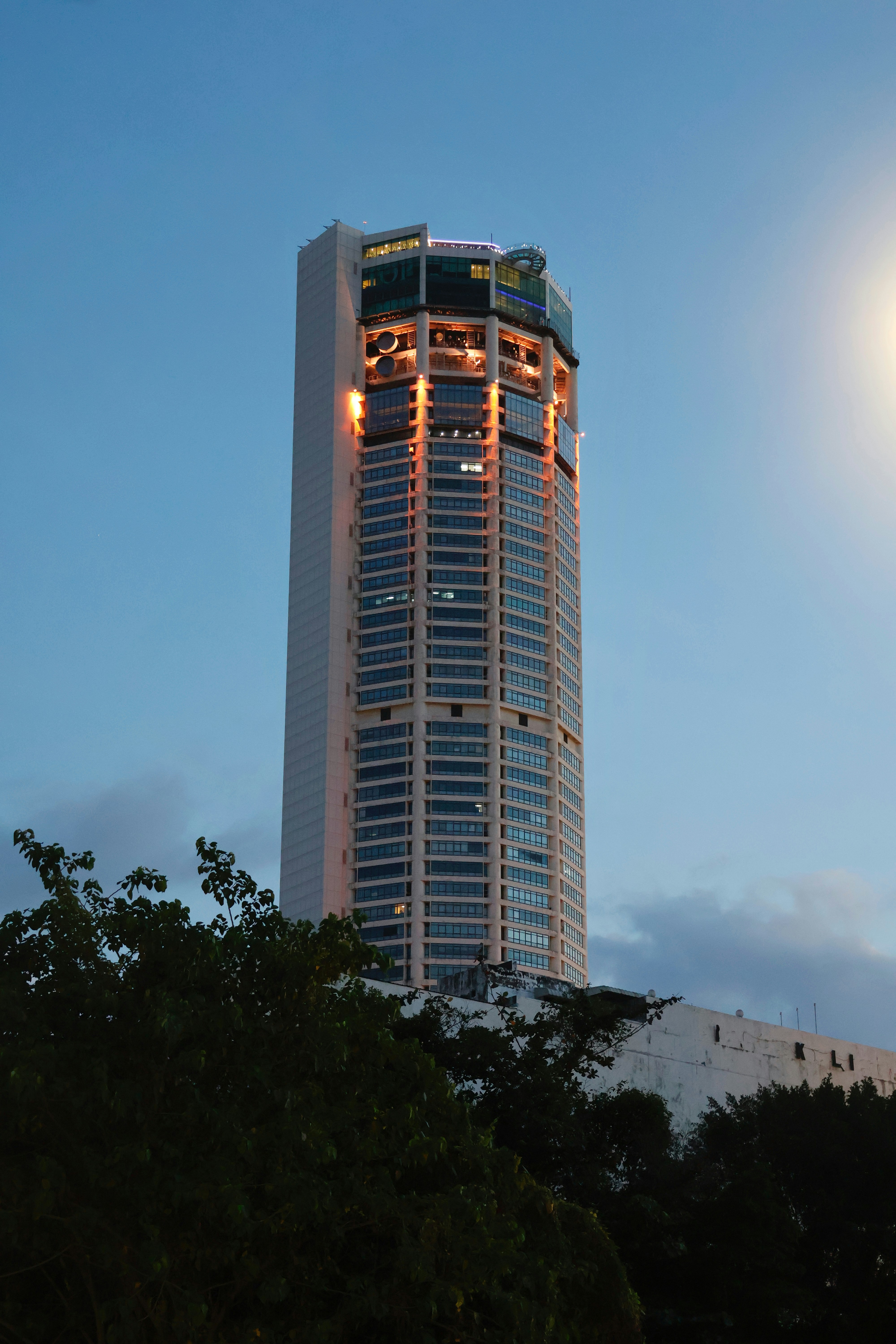 Tall skyscraper with illuminated floors against blue sky