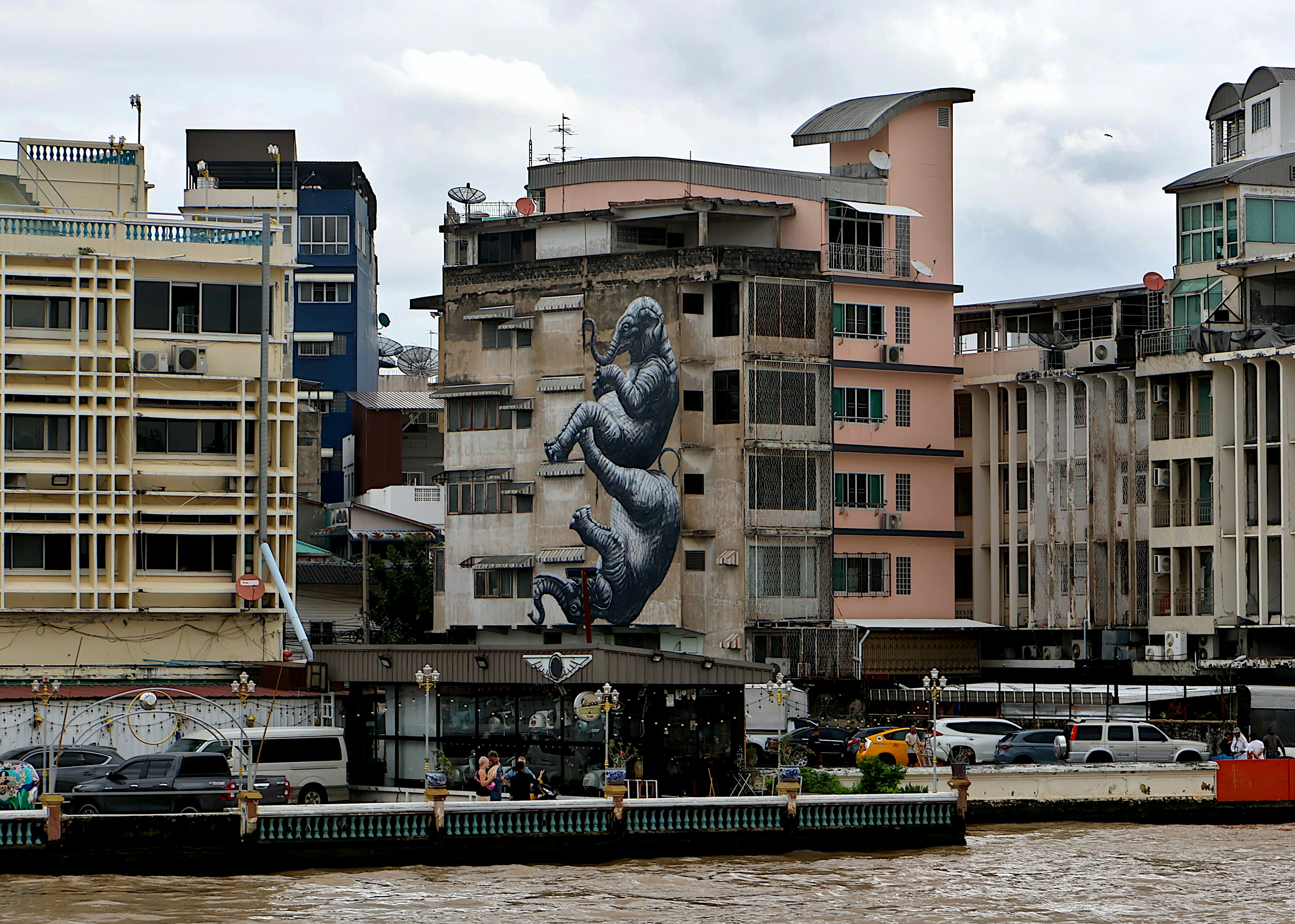 Graffiti mural on building overlooking river with boats