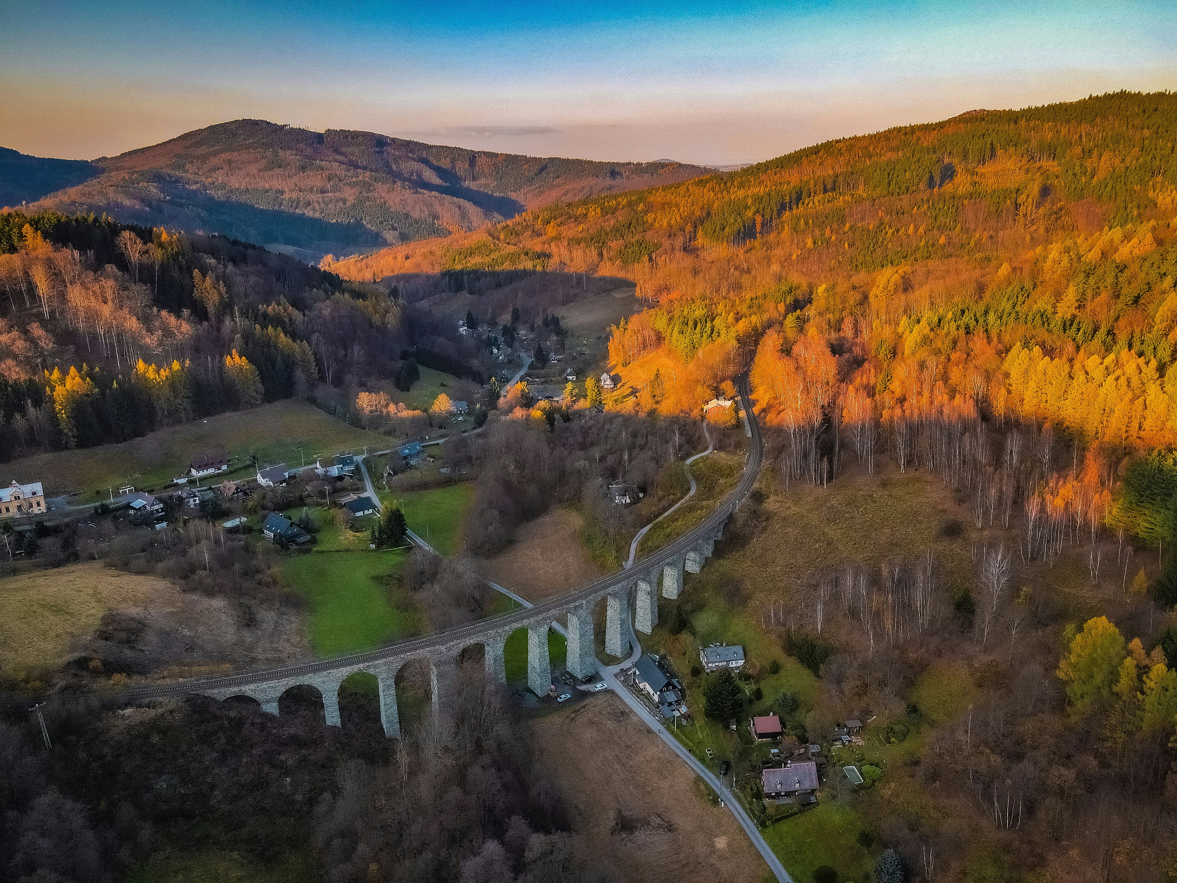 Arched viaduct crosses a valley at sunset