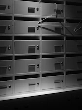 Rows of metal mailboxes with hangers inside shadows