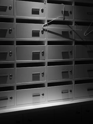 Rows of metal mailboxes with hangers inside shadows