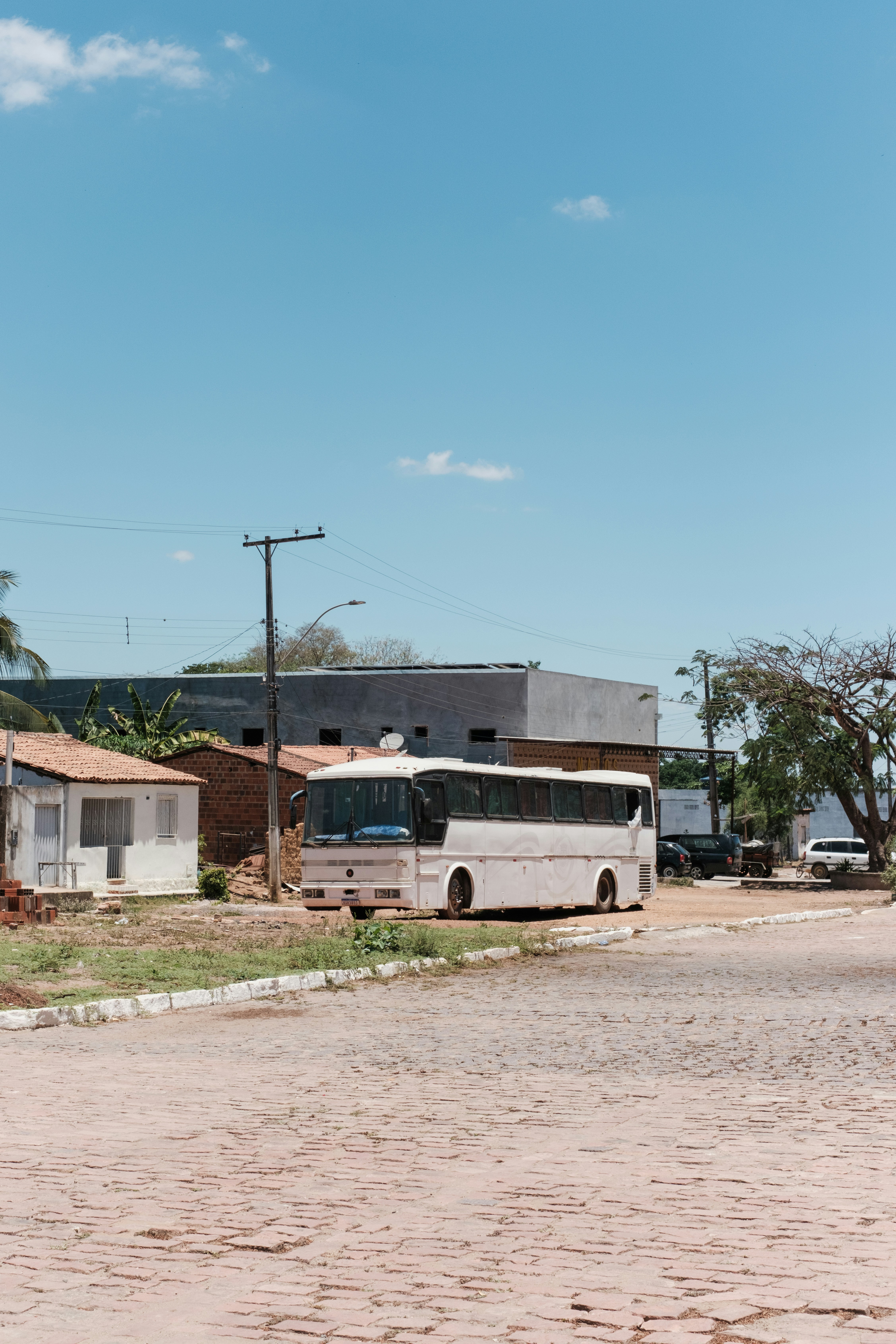 A white bus parked on a cobblestone street.