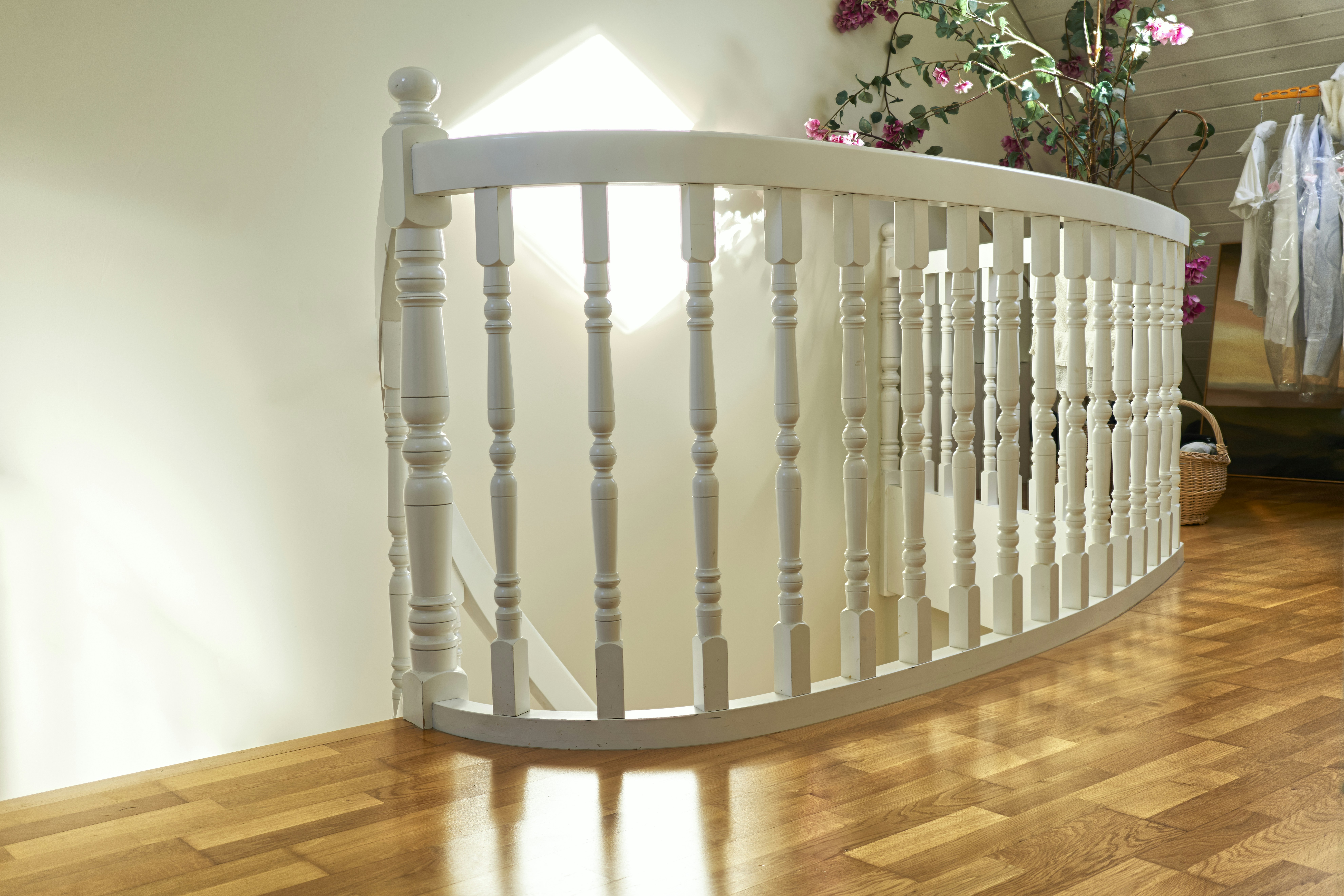 Curved white wooden staircase railing with sunlight