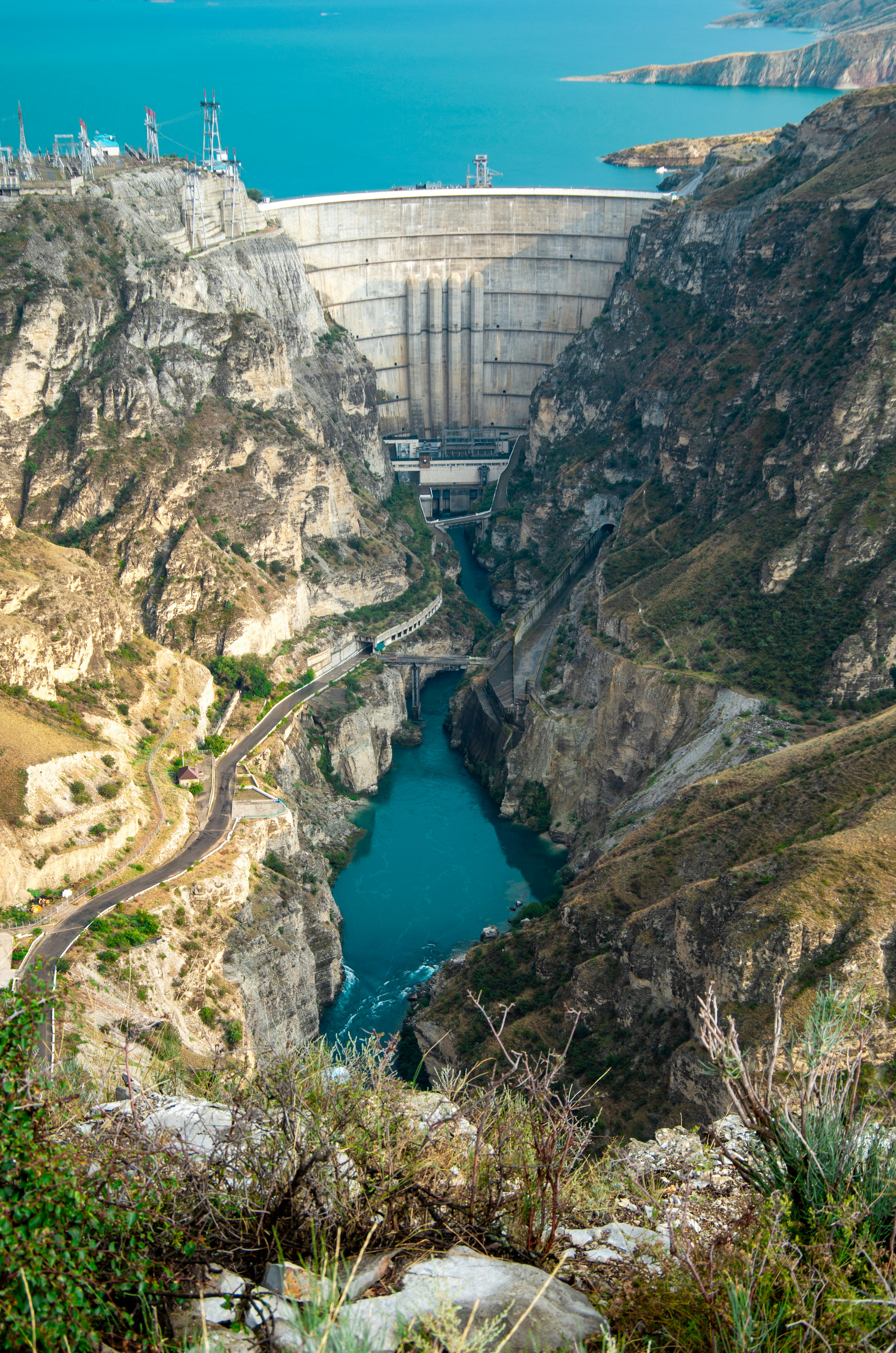Massive concrete dam in a rocky canyon with blue water
