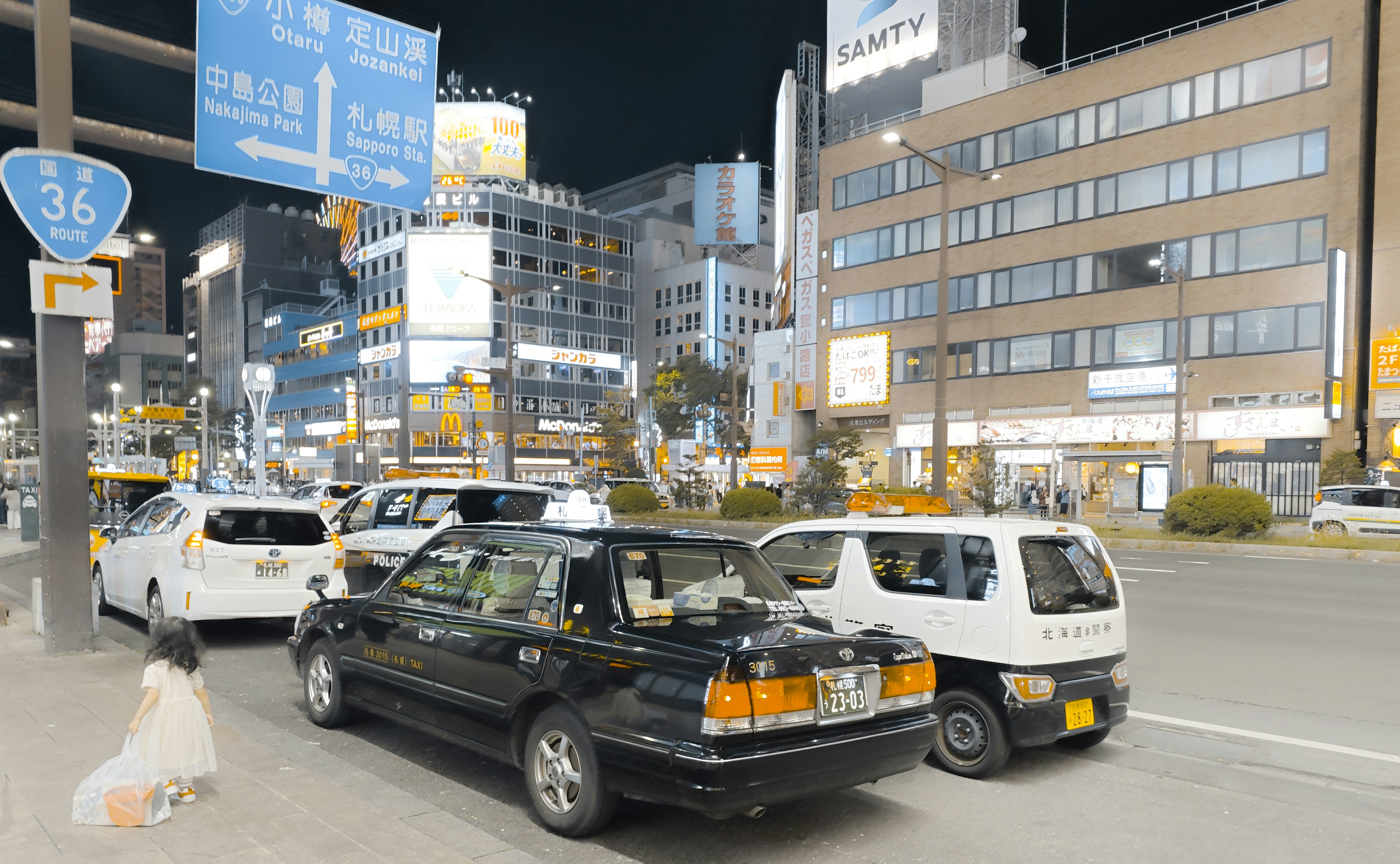 Nachts eine belebte Stadtstraße mit Autos und Gebäuden.