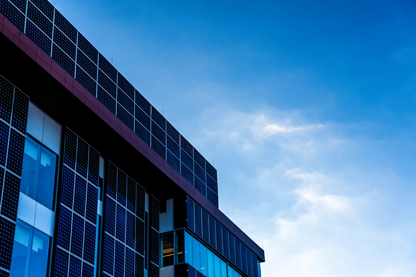 Modern building facade with solar panels against a blue sky