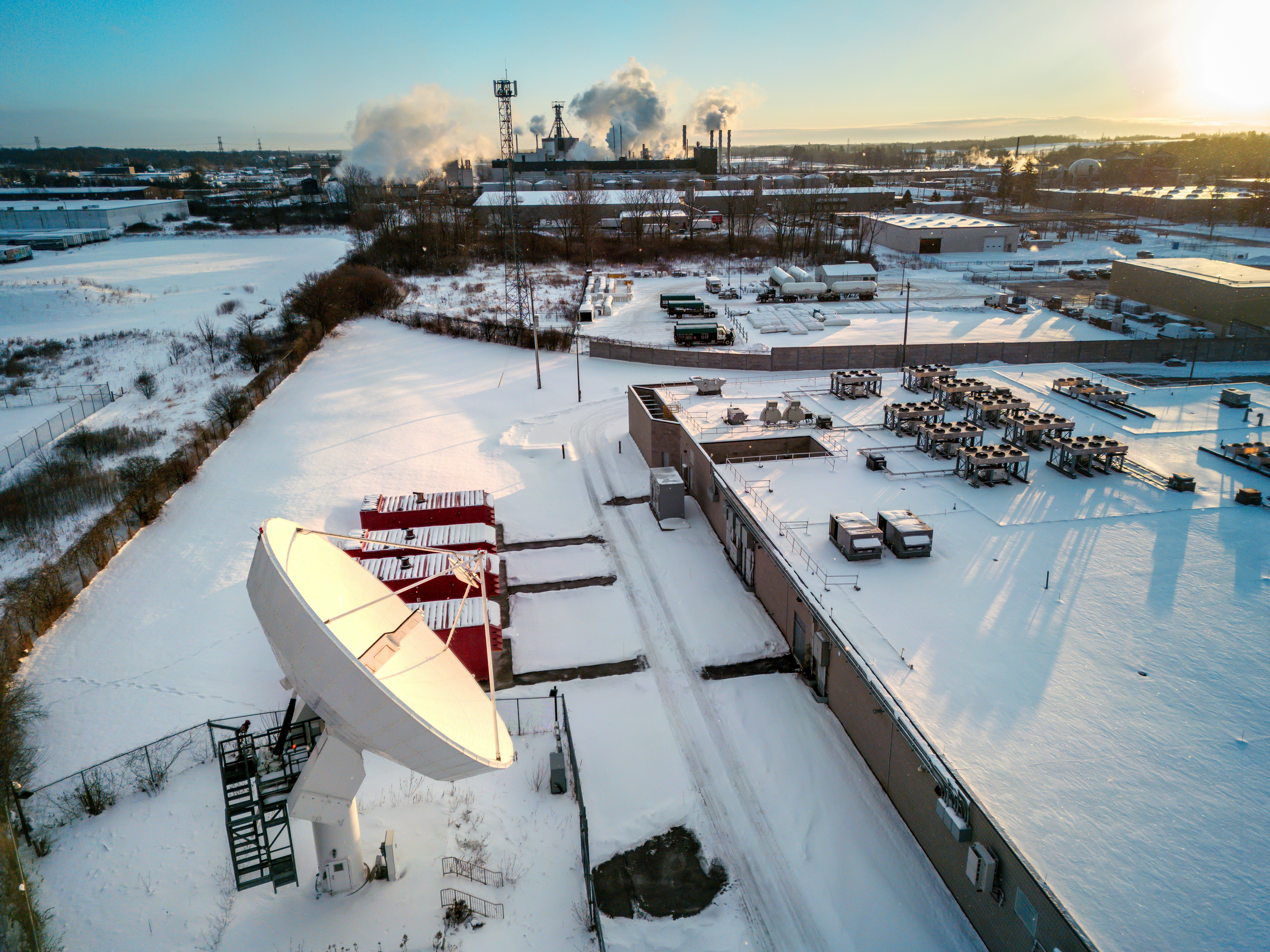 Industrial complex with satellite dish in snowy landscape.