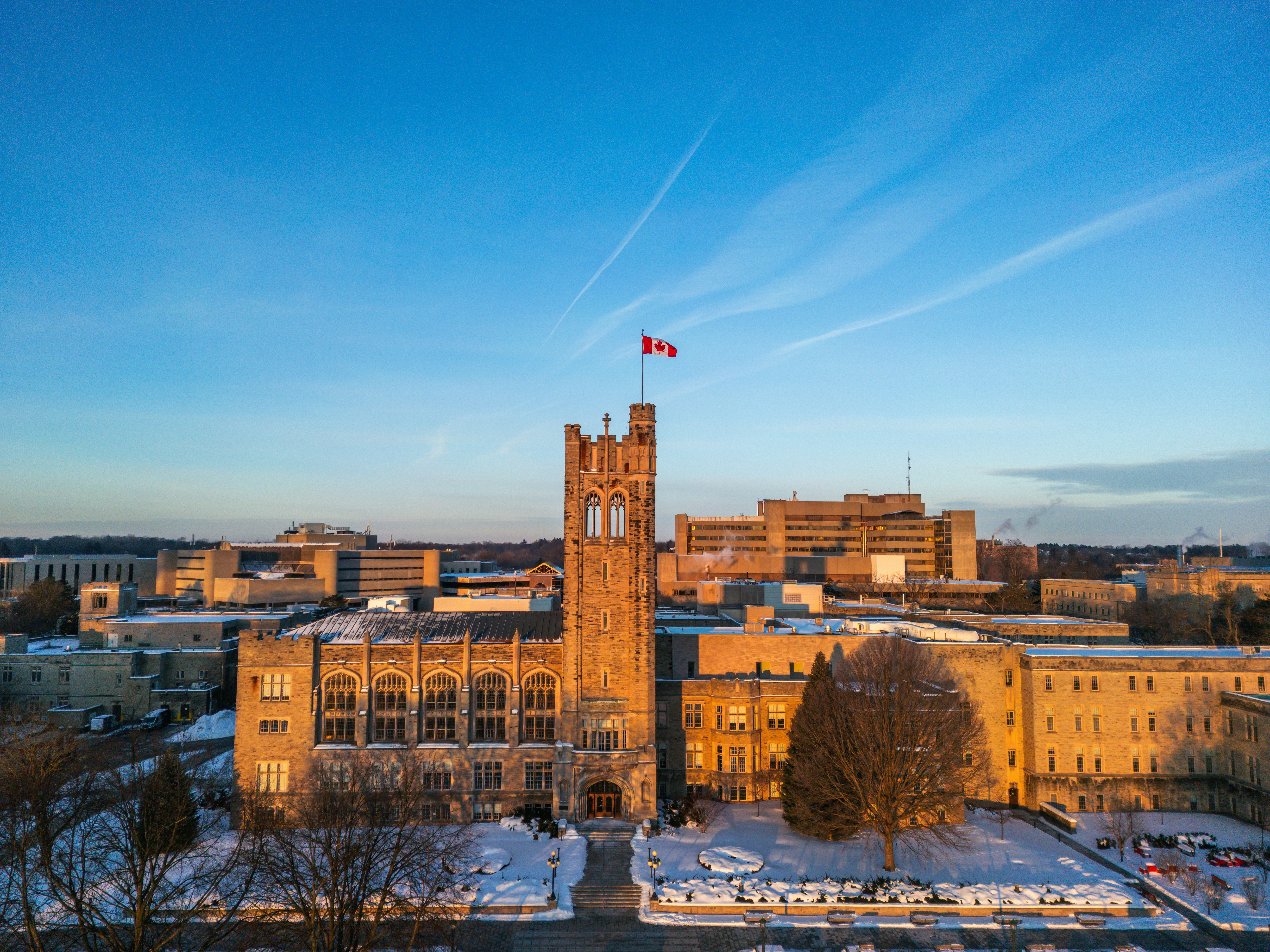 Stone building with canadian flag under blue sky.