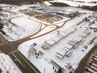 Aerial view of a snowy industrial complex with trucks.