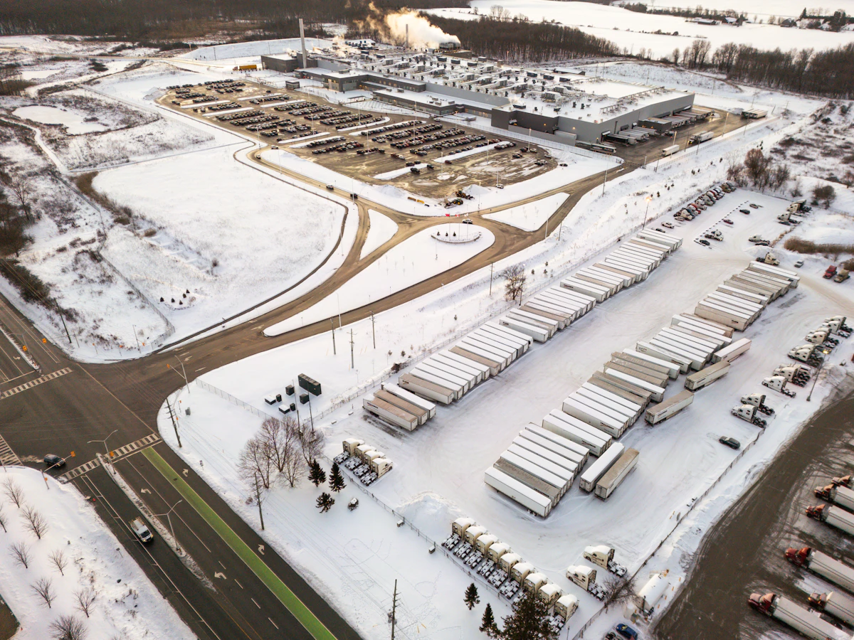 Aerial view of a cold-storage logistics complex with refrigerated trucks in snow