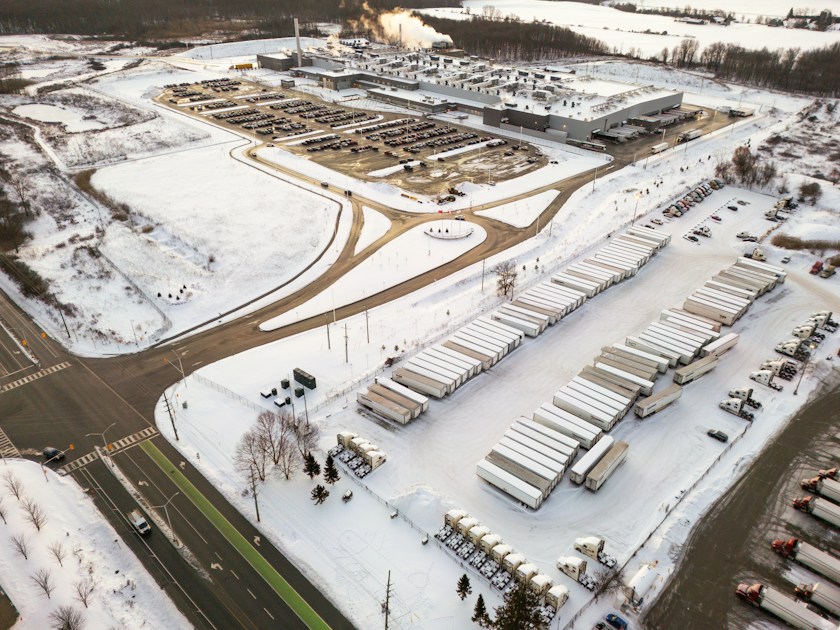 Aerial view of a snowy industrial complex with trucks