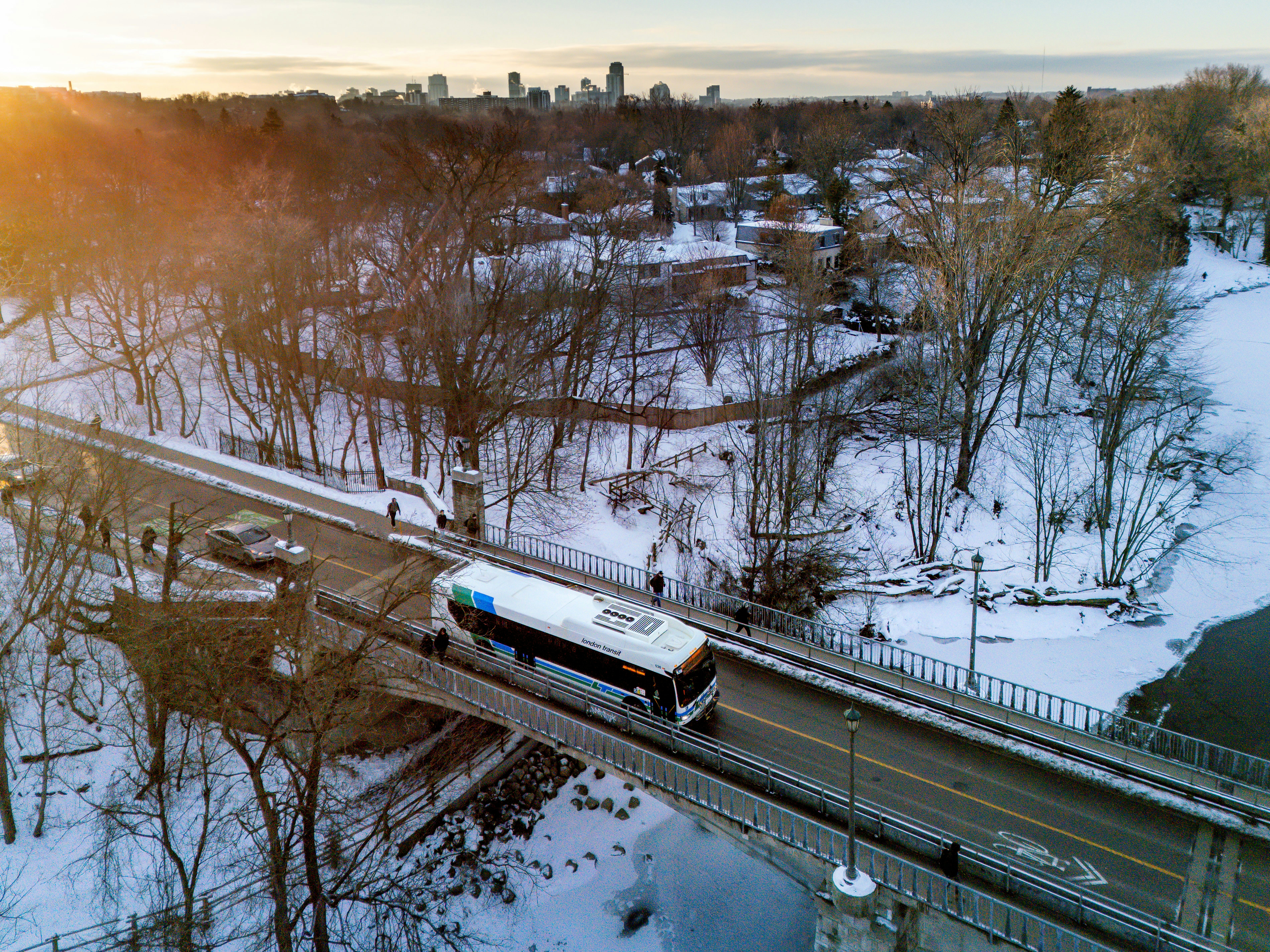 Bus crossing a snow-covered bridge in a winter landscape.