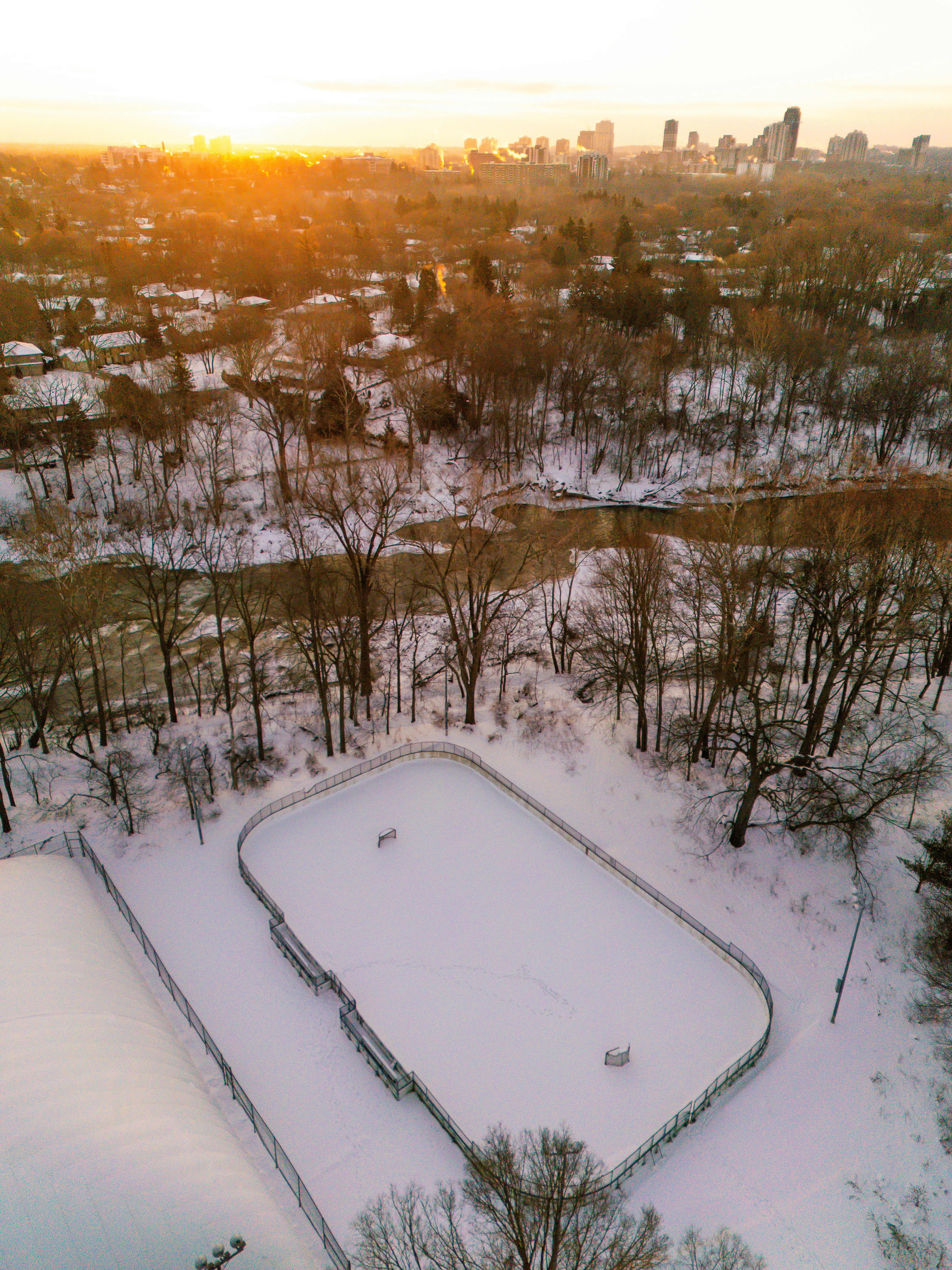 Snowy park with outdoor skating rink at sunset