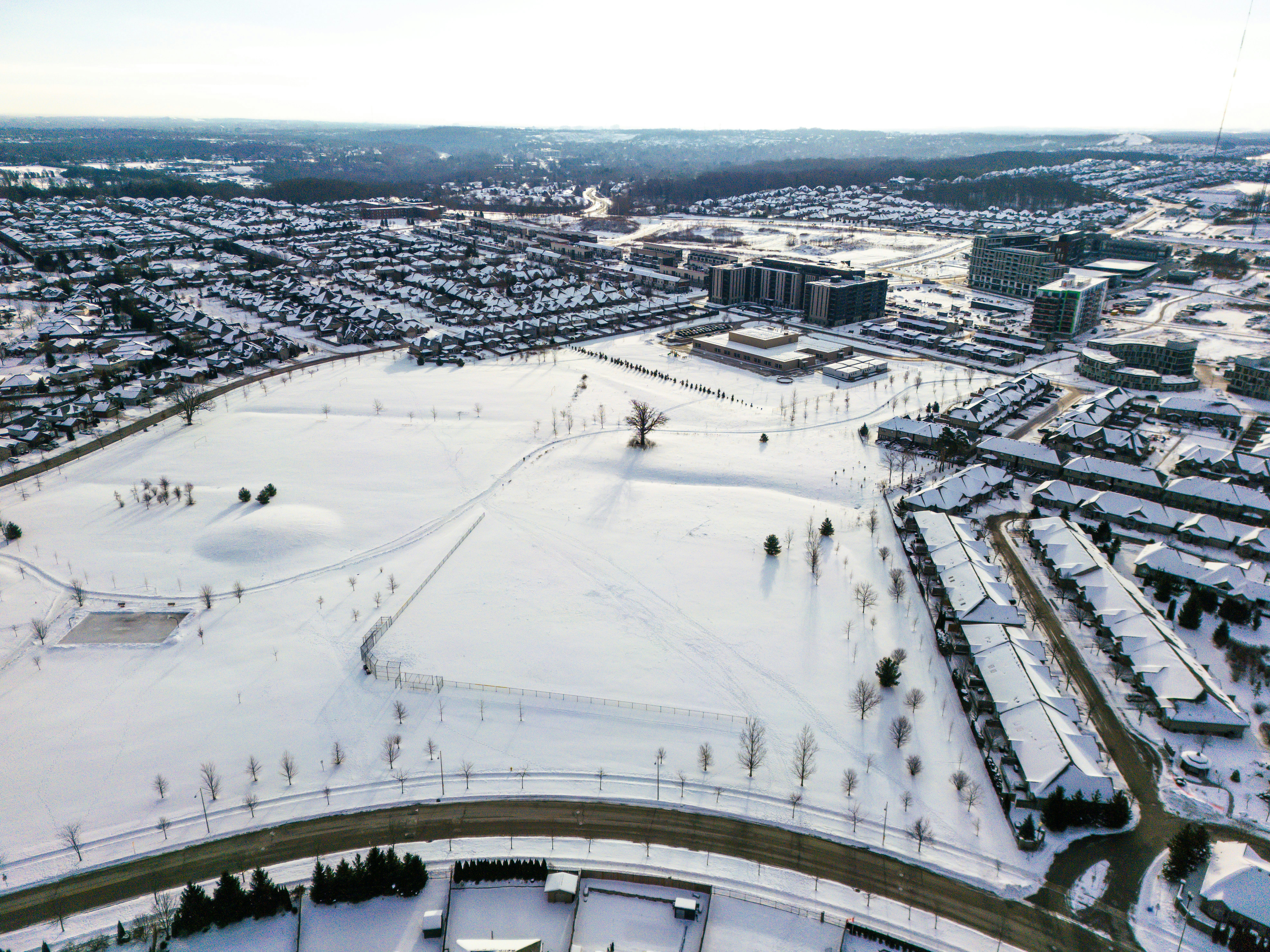 Aerial view of a snow-covered suburban neighborhood and park.