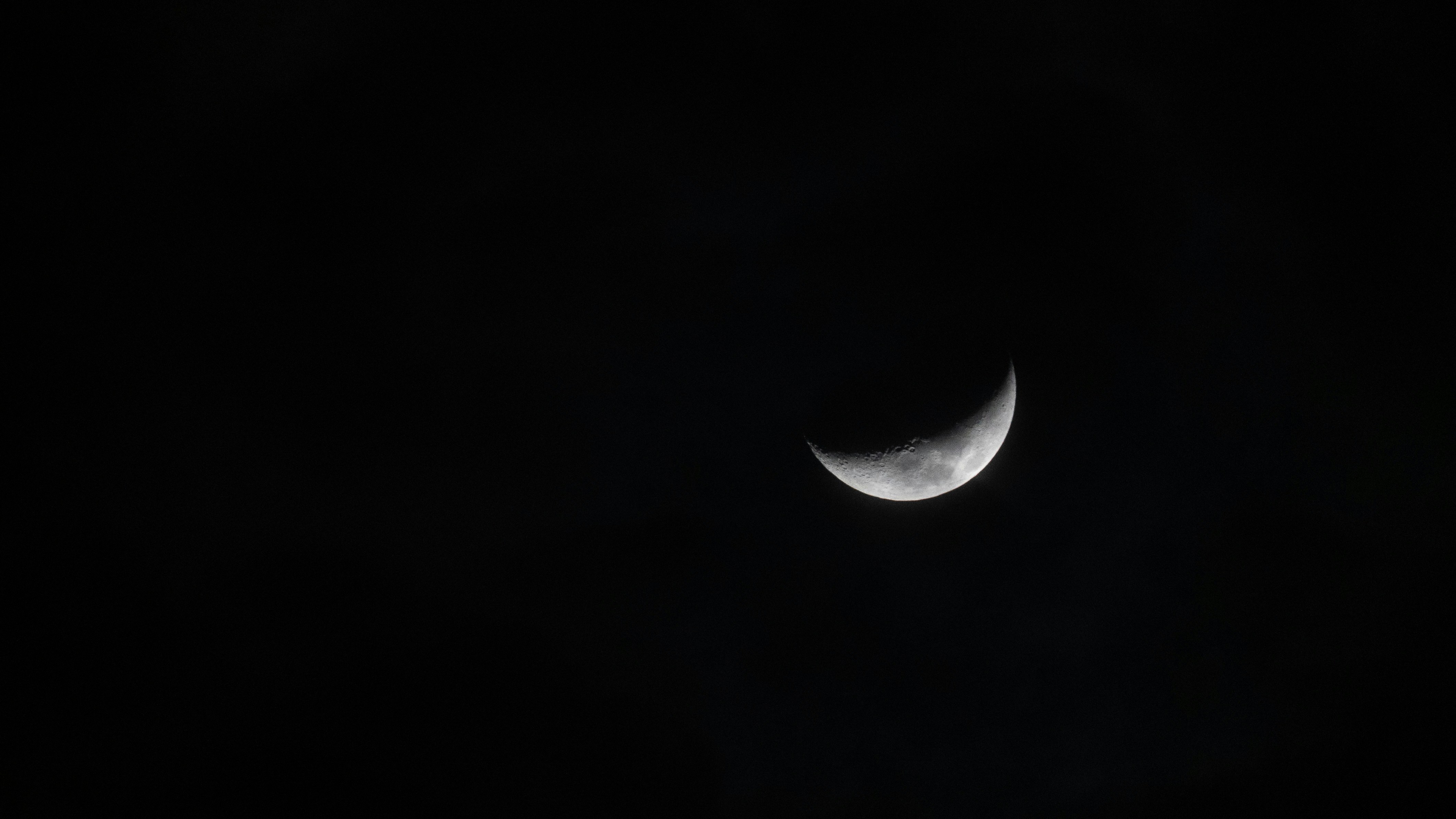 A crescent moon hangs in the dark night sky.