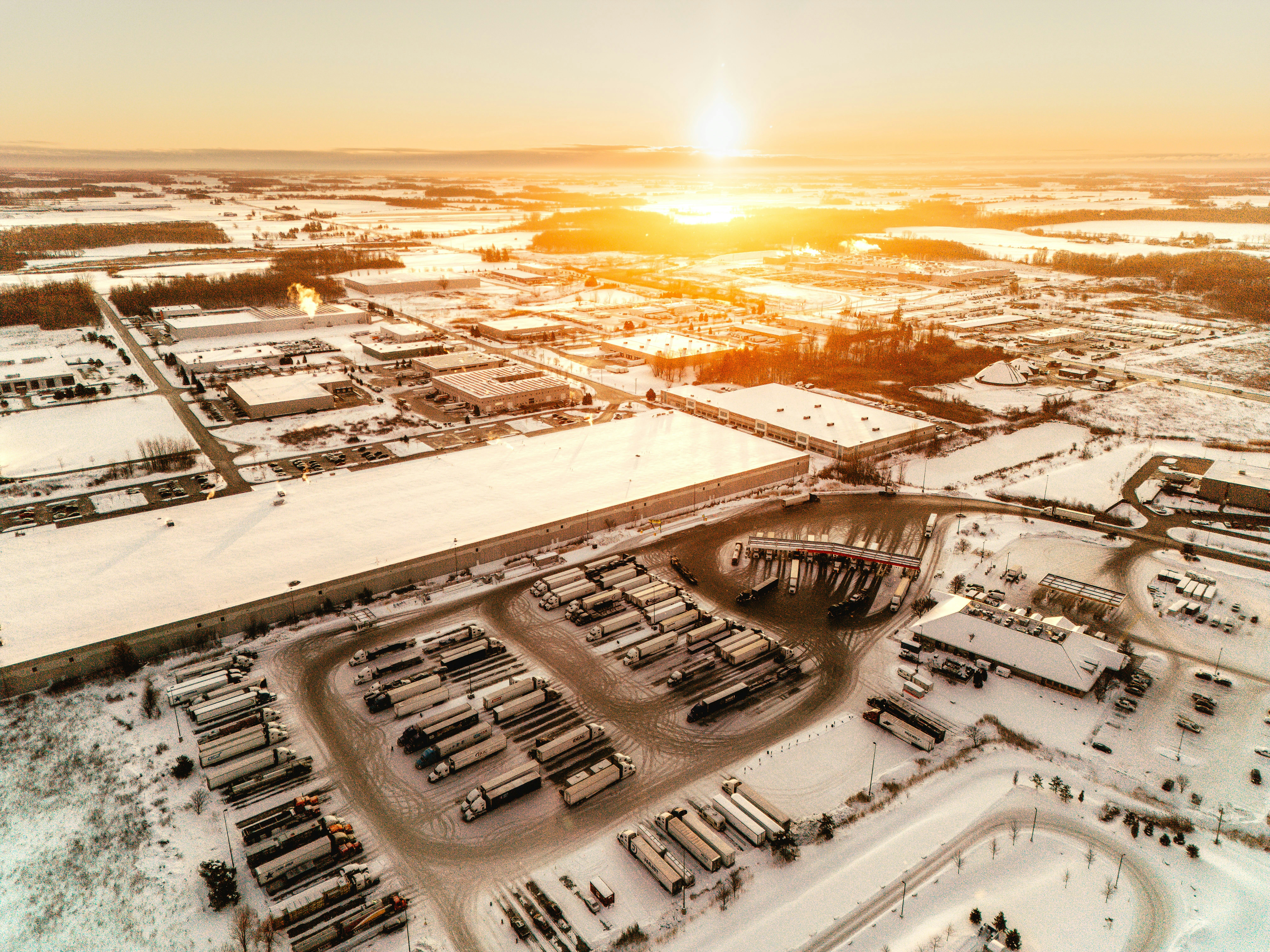 Aerial view of a snow-covered industrial park at sunset.