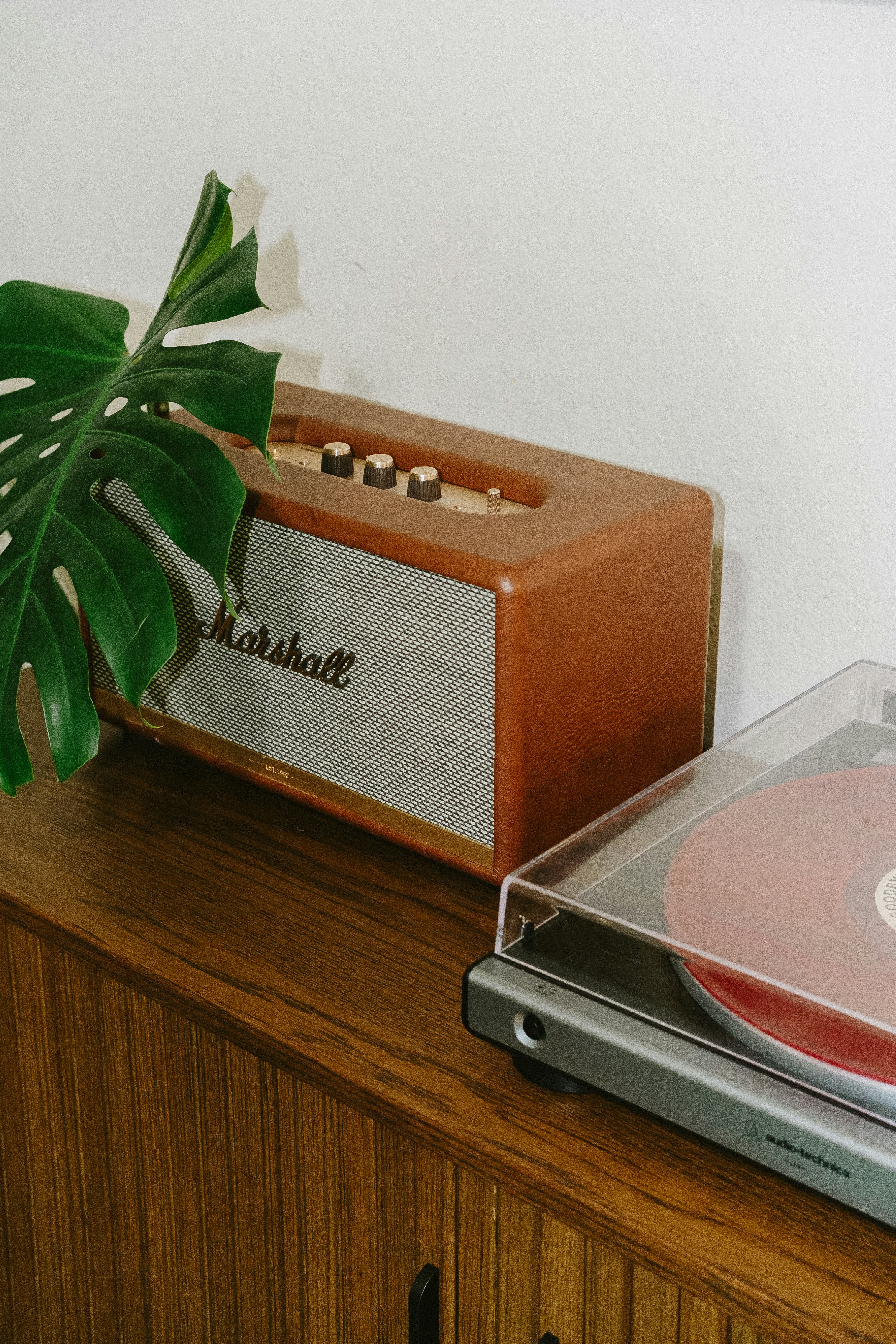 Un haut-parleur Marshall et un tourne-disque sur un meuble en bois.