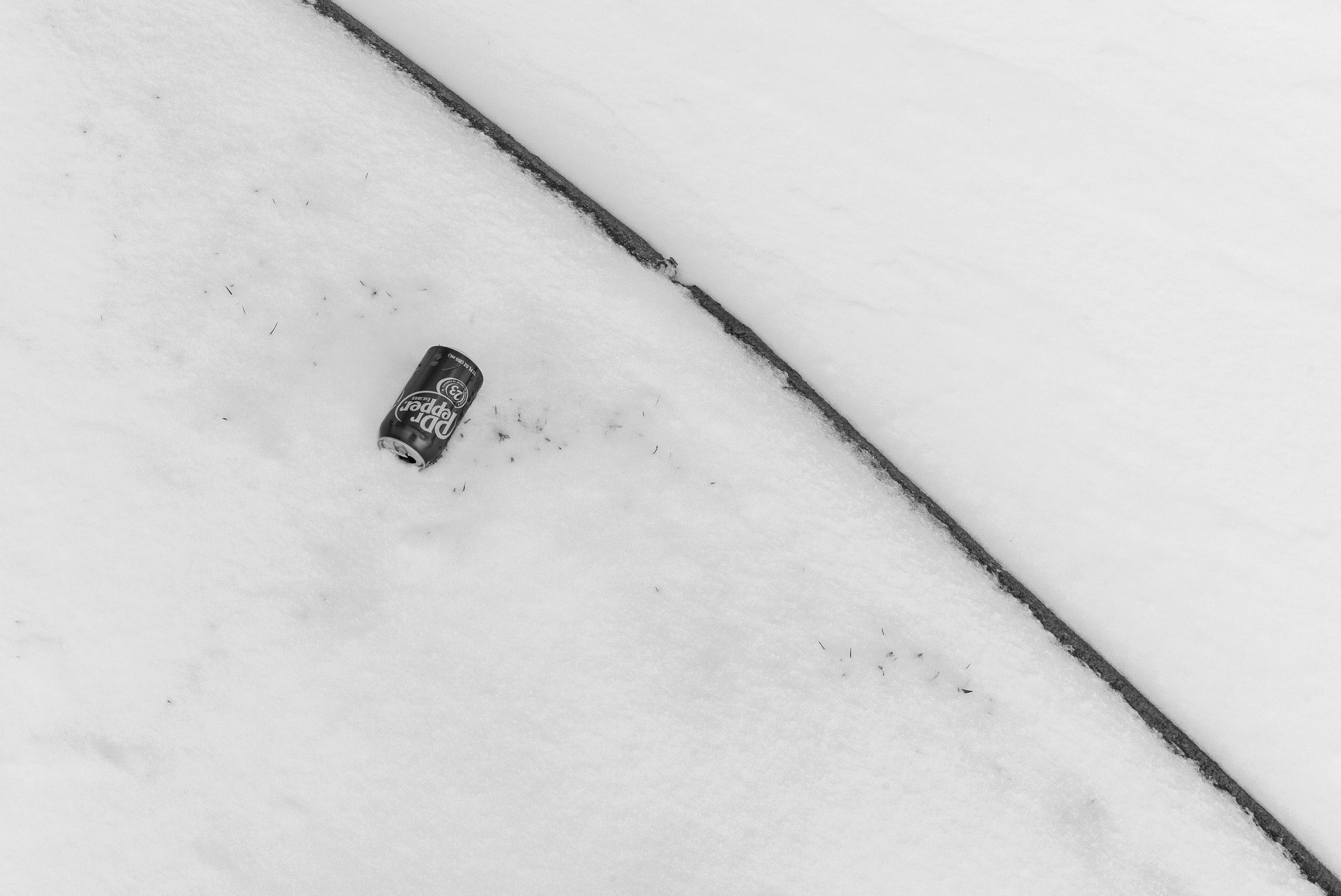 Une seule canette de soda repose sur une surface enneigée.