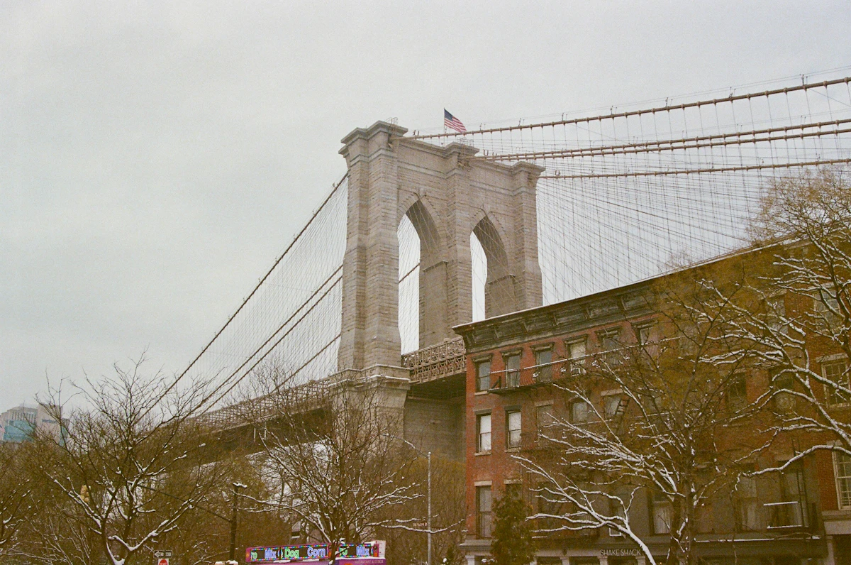 Brooklyn Bridge tower under a grey winter sky with a dusting of snow