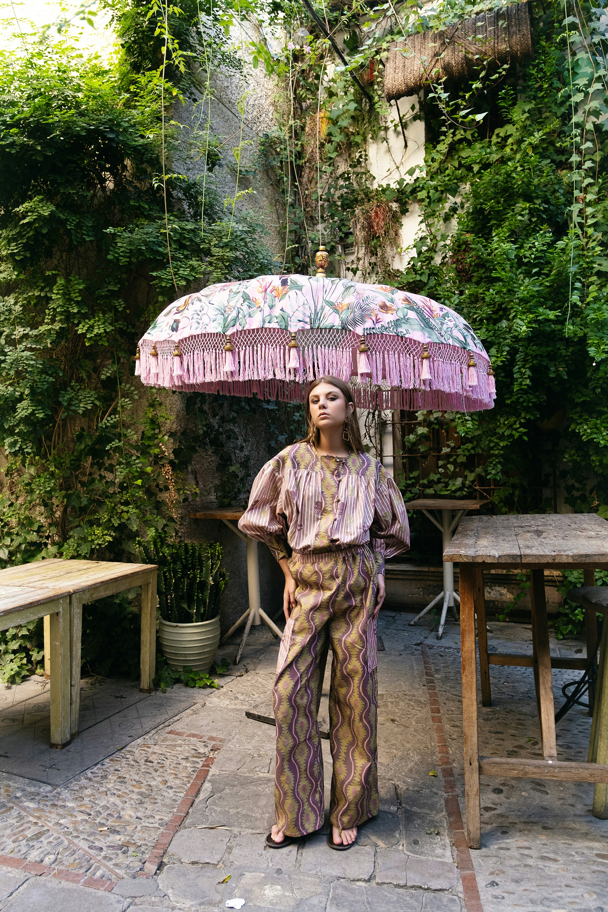 Woman posing under a decorative umbrella in a courtyard.