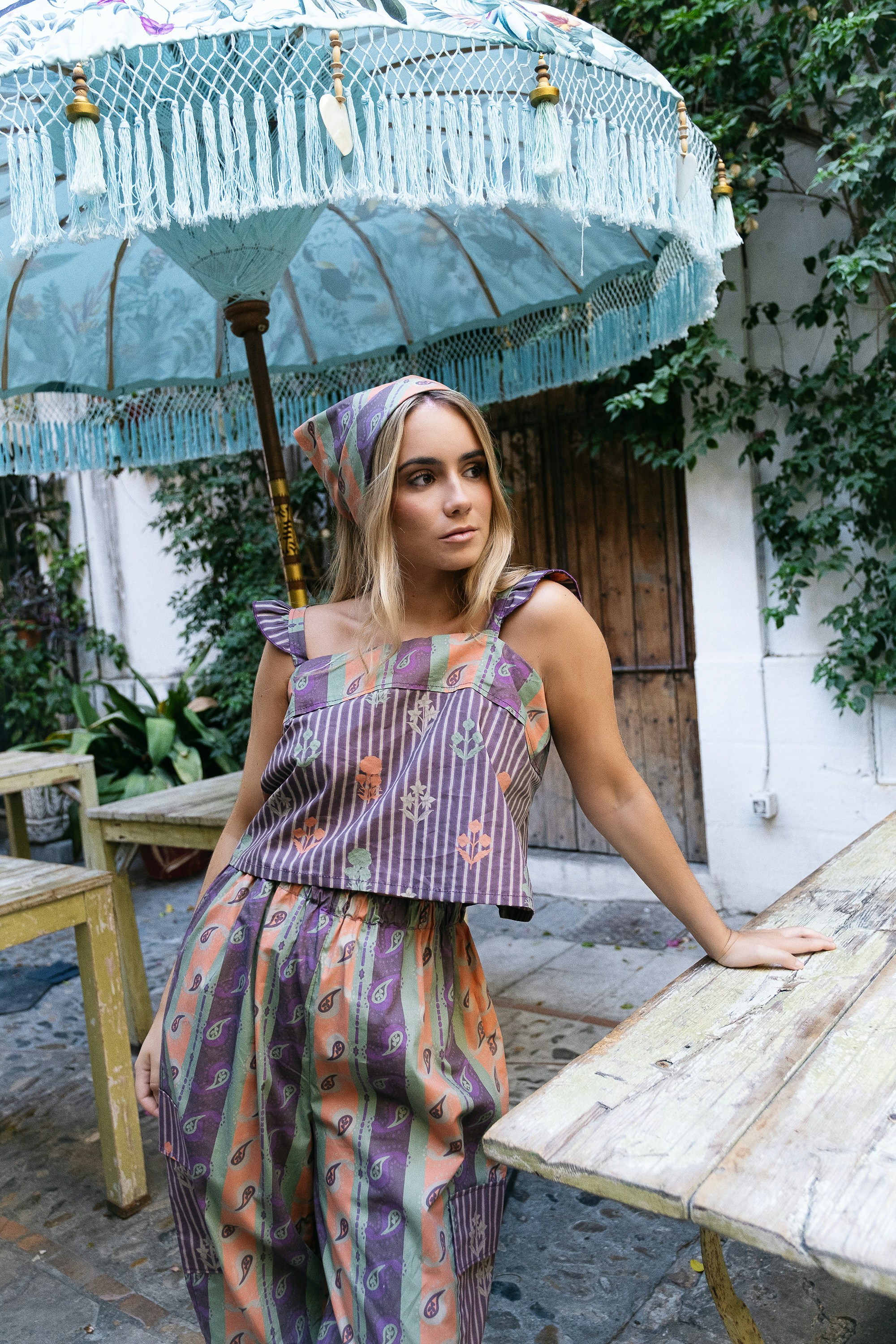 Woman in patterned outfit under a decorative umbrella
