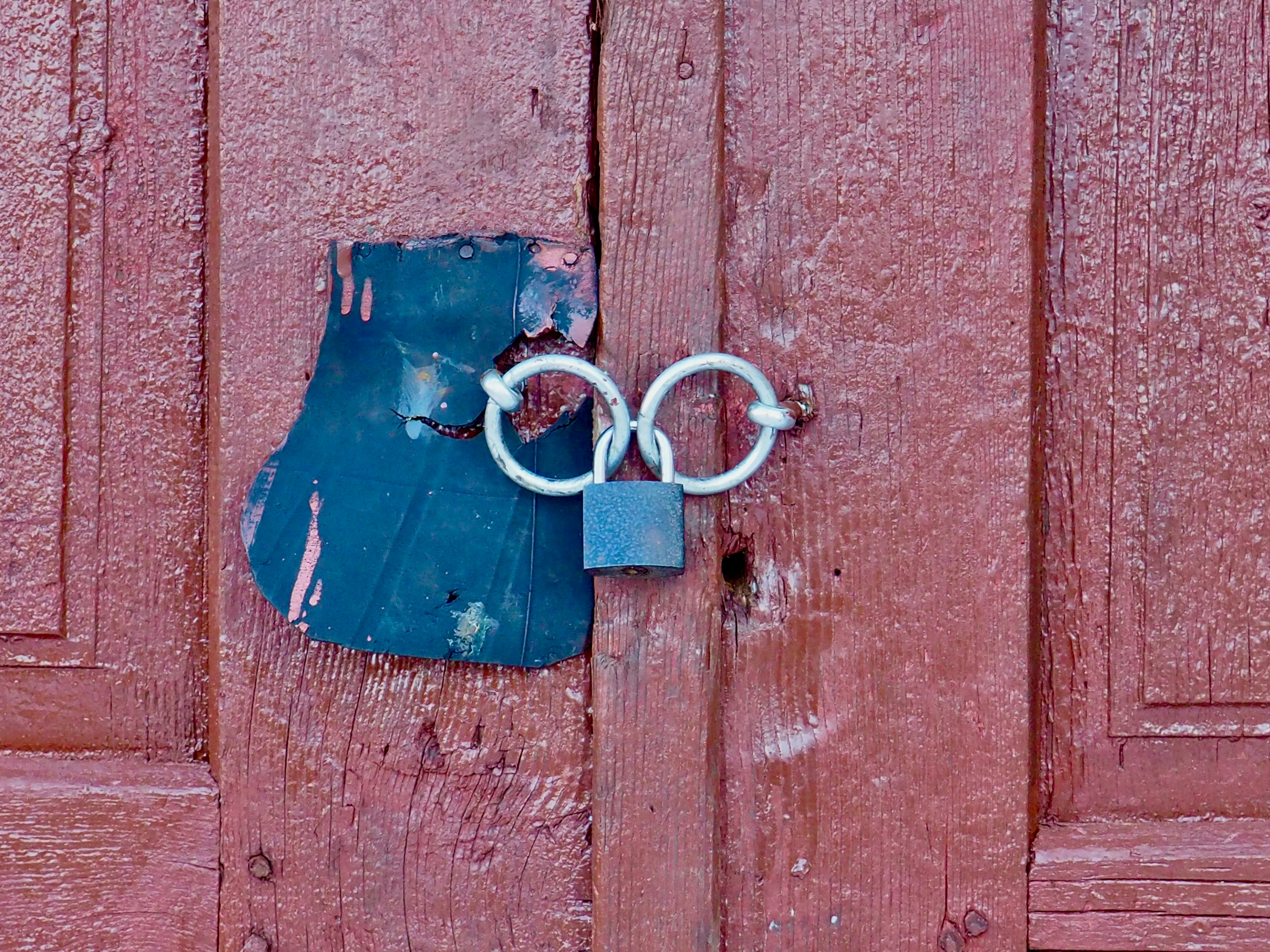 A weathered red door with a locked hasp.