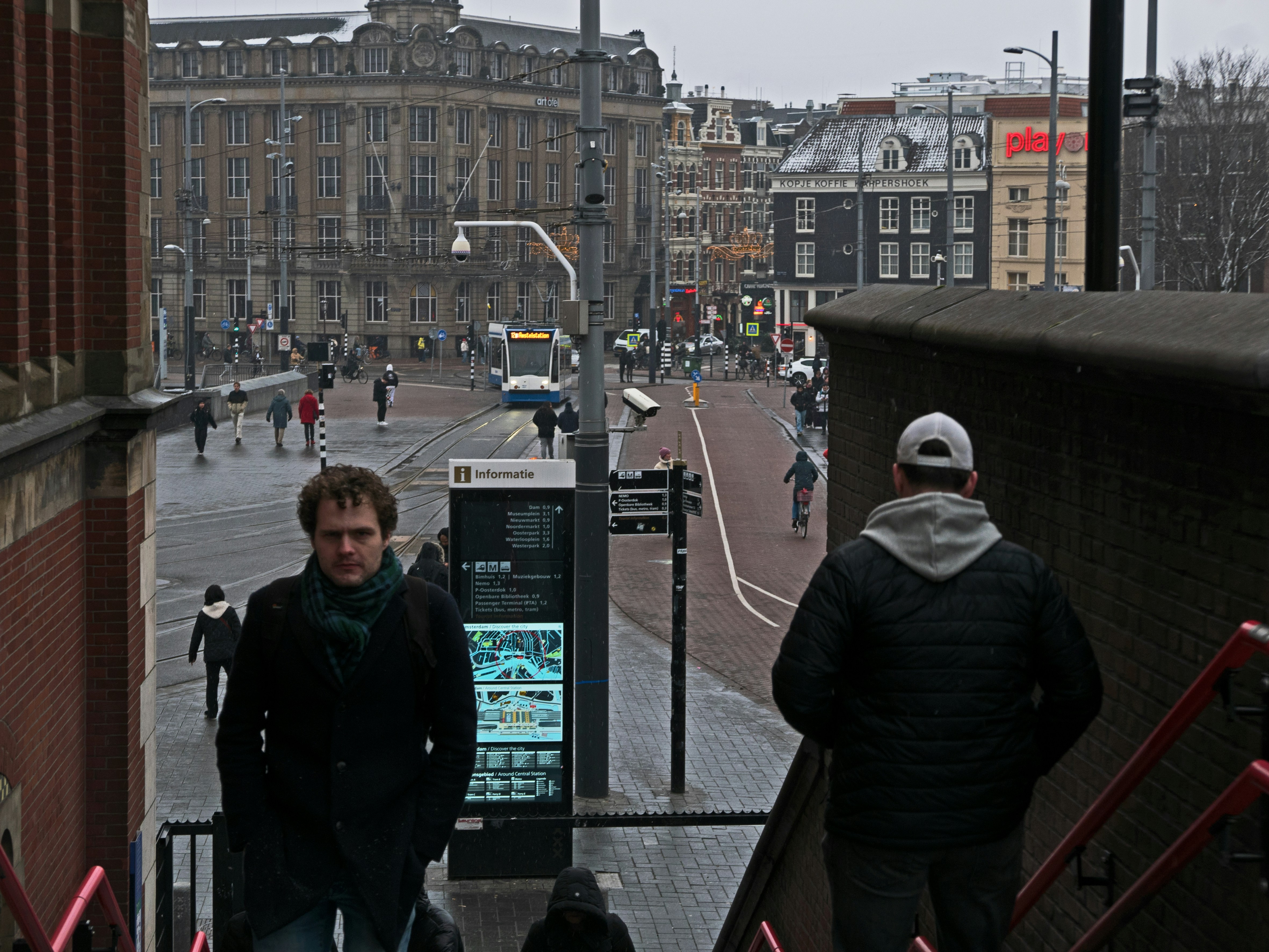 Two men walk down stairs with city buildings in background