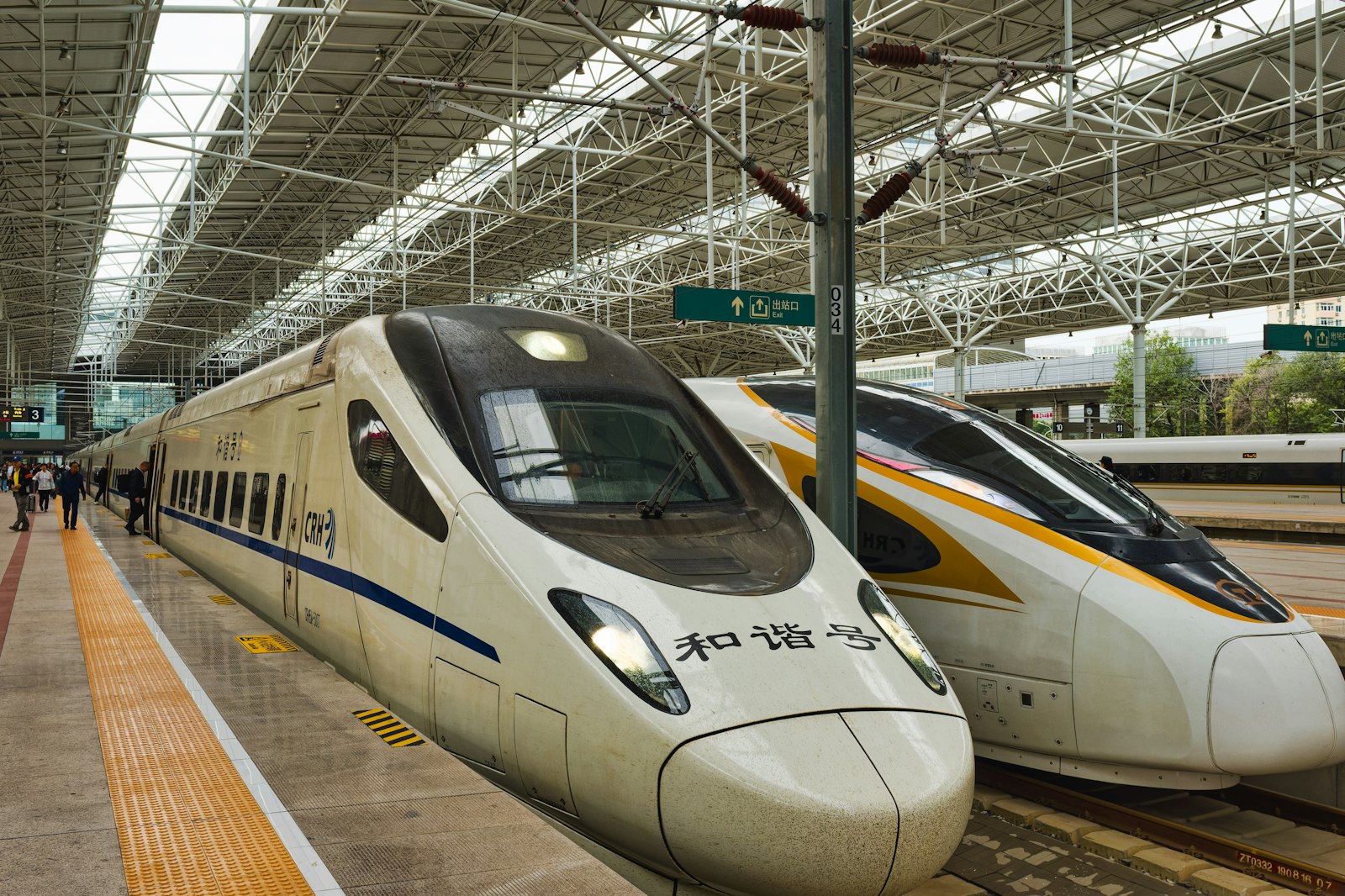 Two white high-speed trains waiting at a covered platform in a Beijing railway station