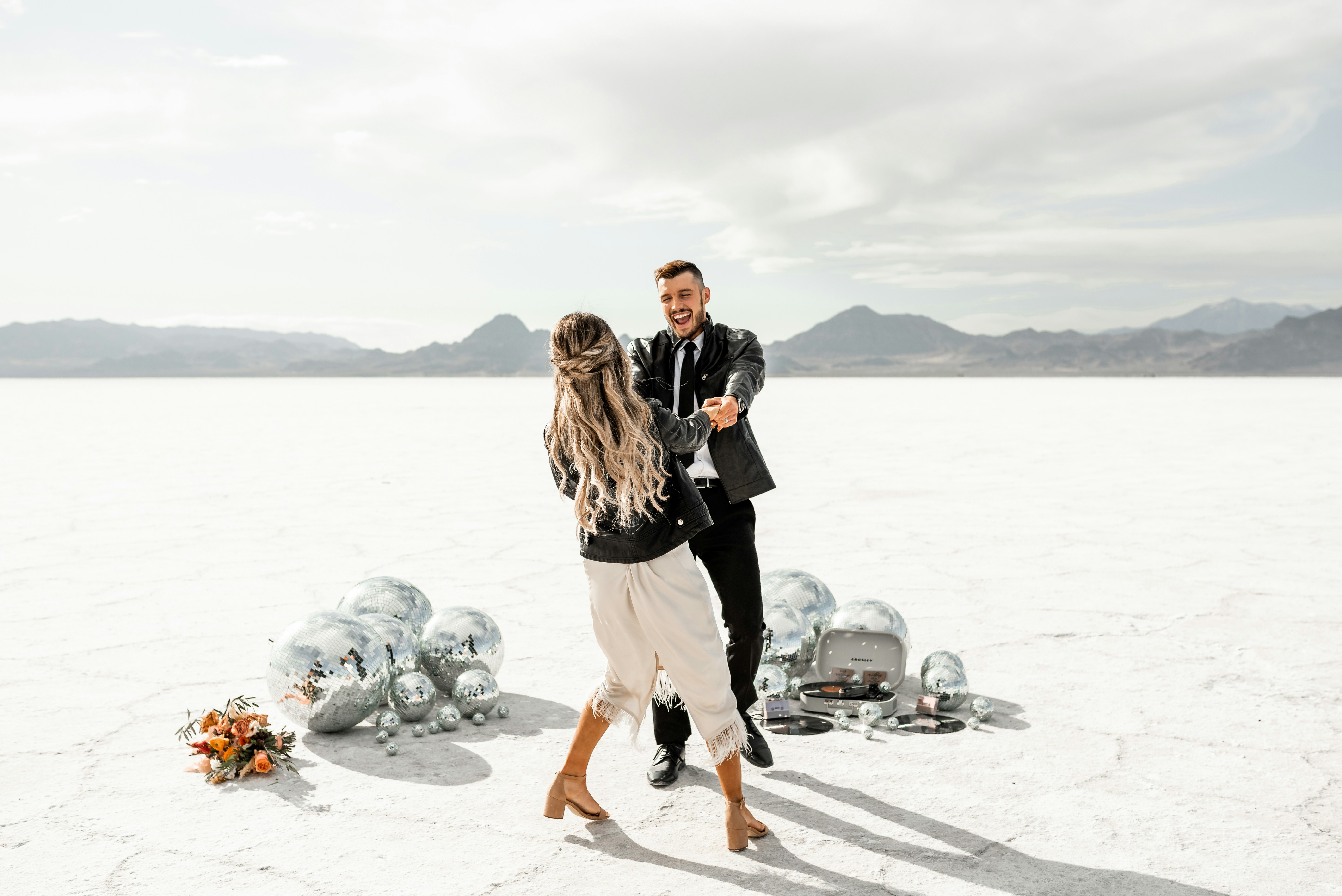 Paar, das in einer Wüste mit Discokugeln tanzt