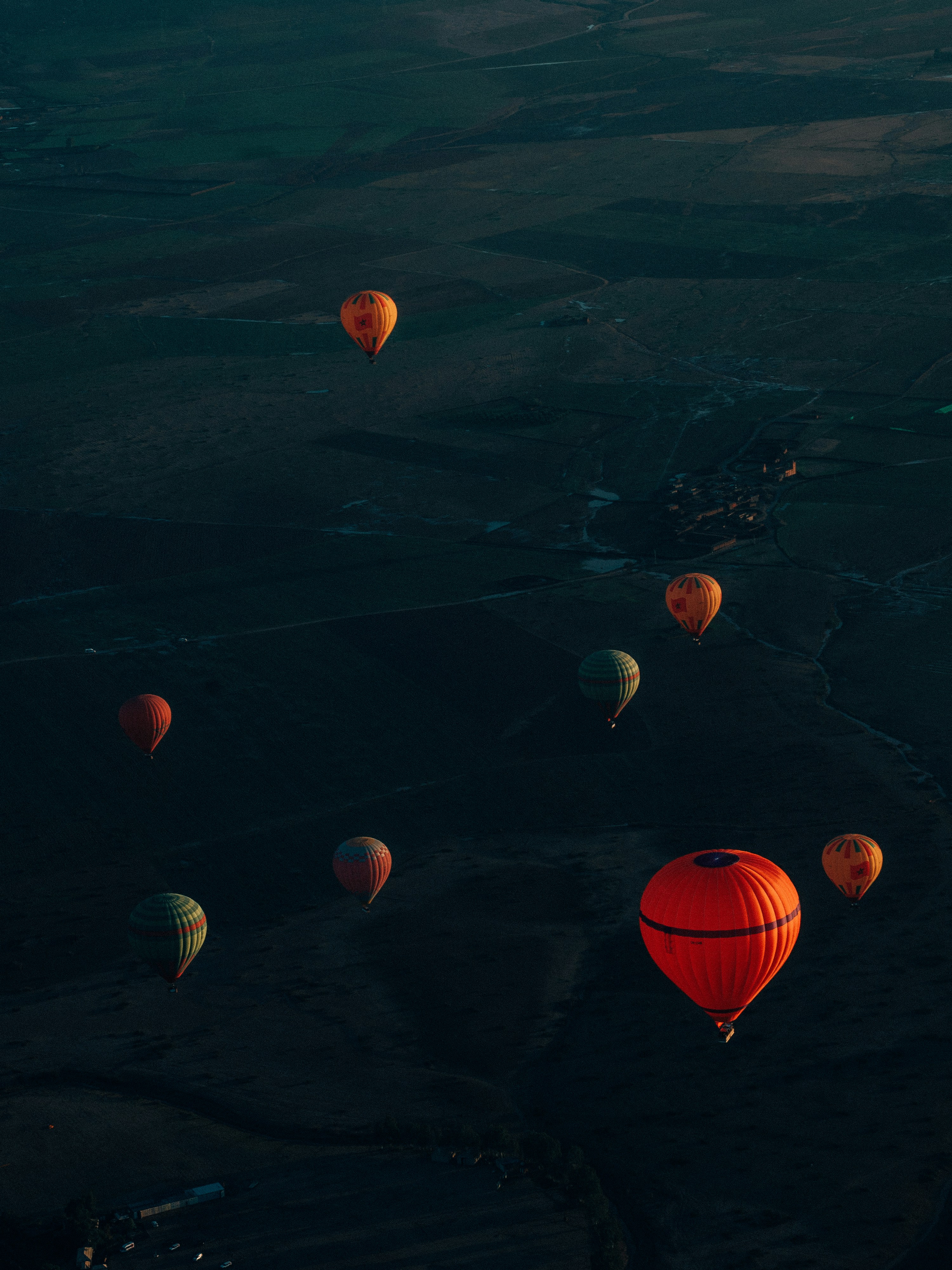 Mongolfiere fluttuano su un paesaggio buio all'alba.