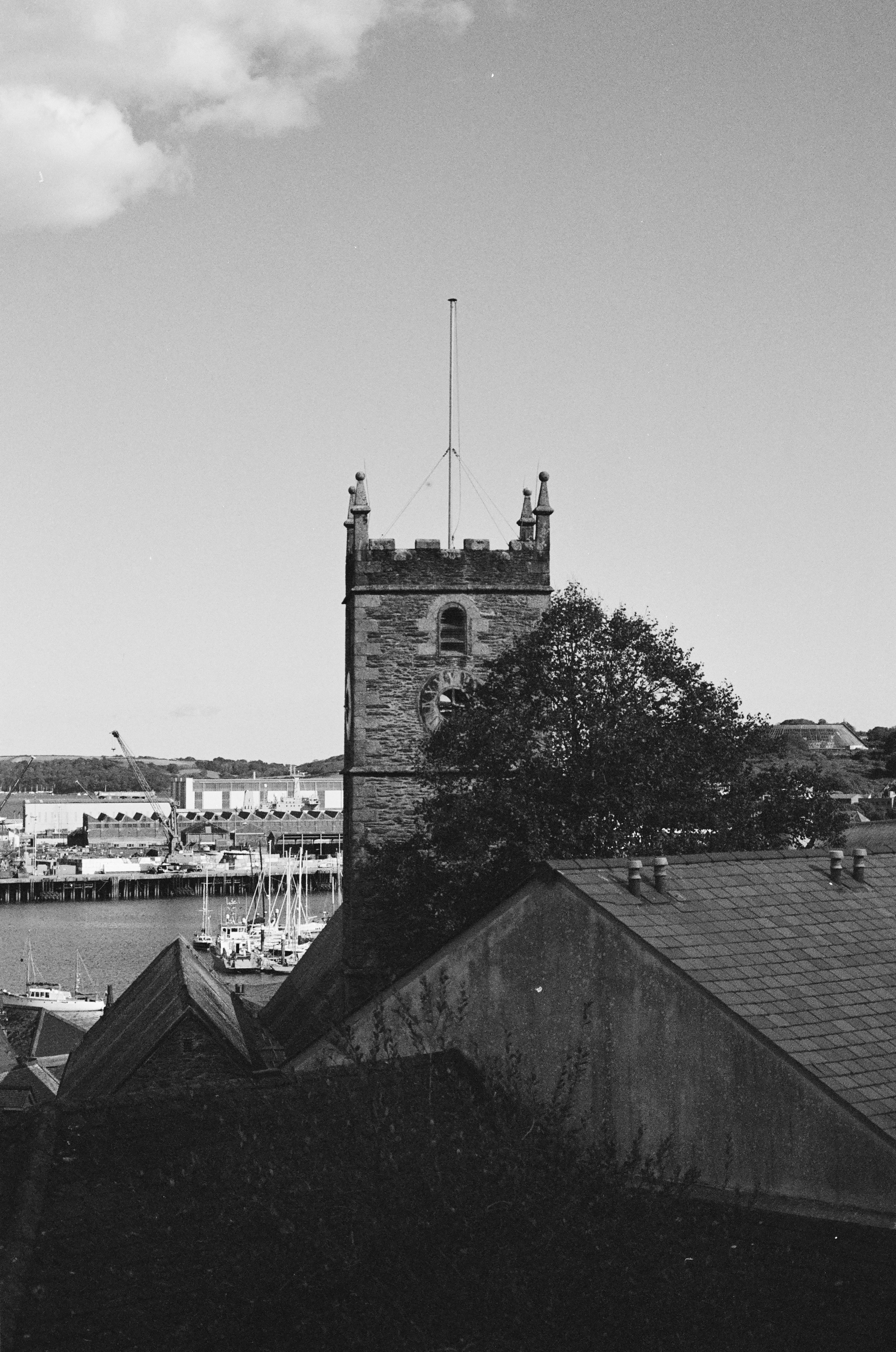 Stone church tower overlooks a harbor with boats.