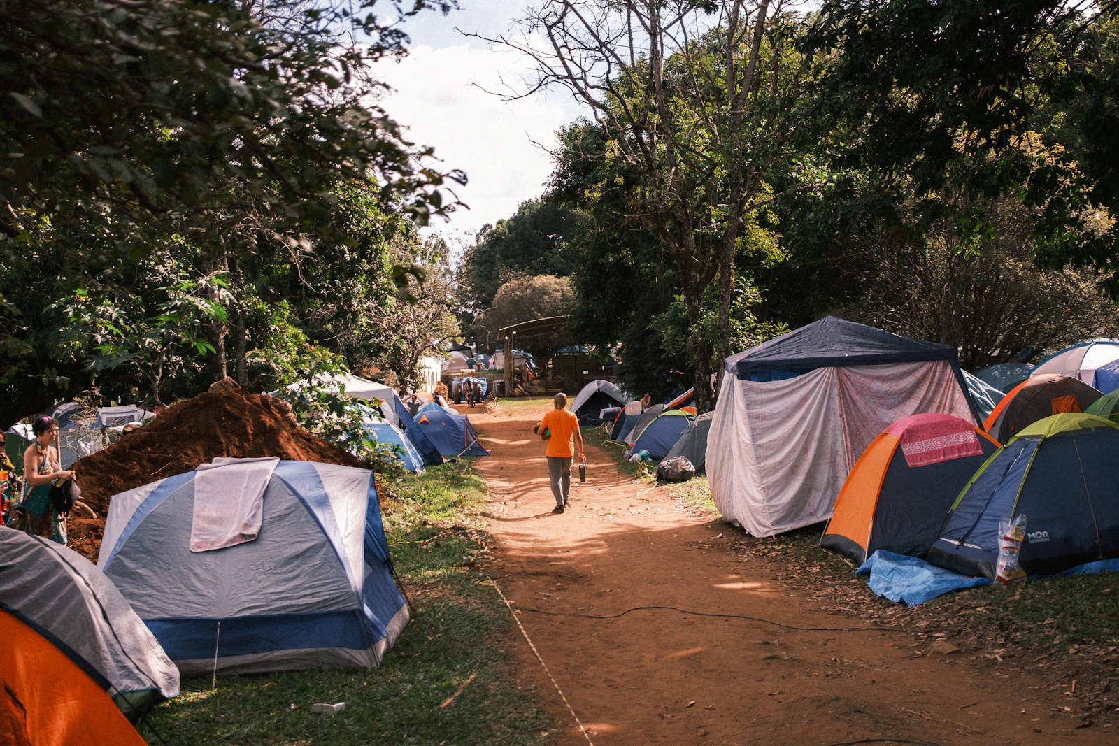 A forest campsite with several tents arranged along a clear walking path