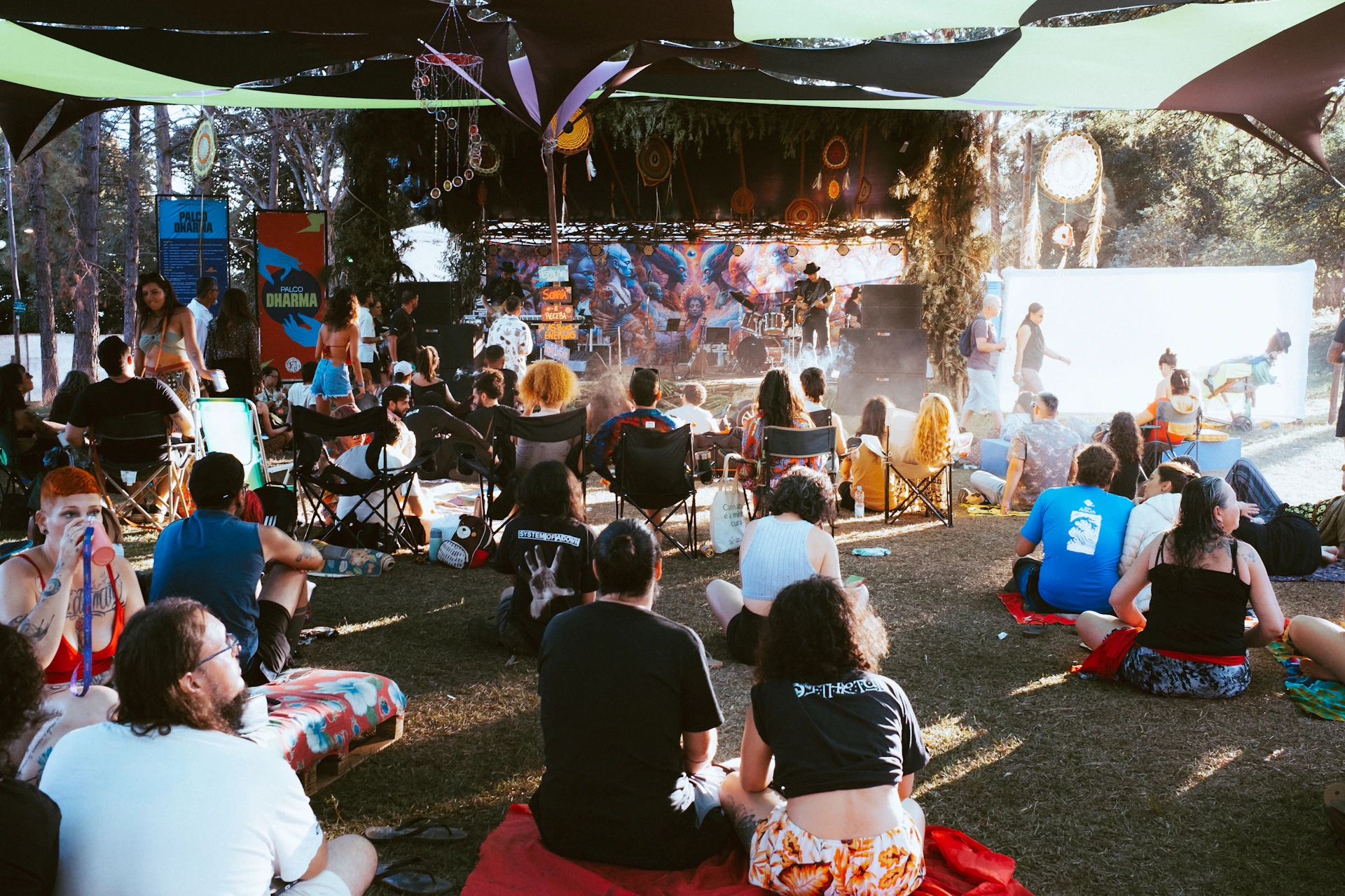 People gathered outdoors watching a performance on stage.