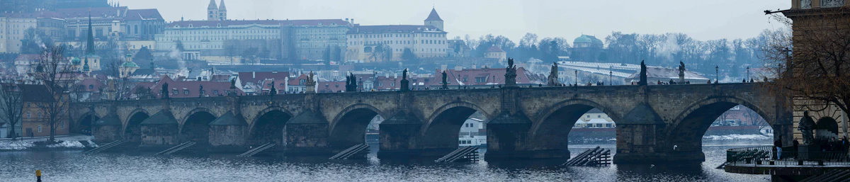 Traveler reading a paper map on Charles Bridge with the Malá Strana bridge towers behind them