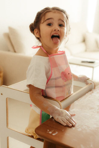 A young girl with flour on her face and hands
