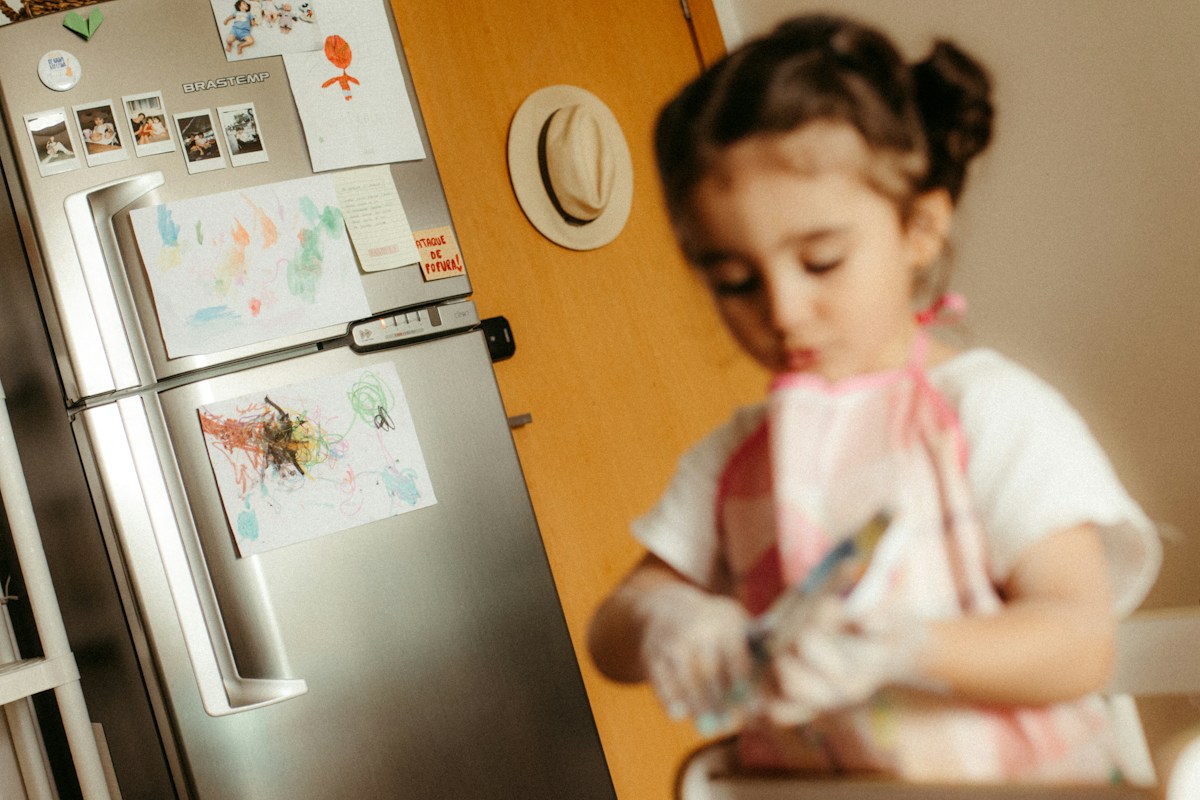 Young girl in apron washing hands at kitchen sink, illustrating family fitness challenge ideas for healthy habits.