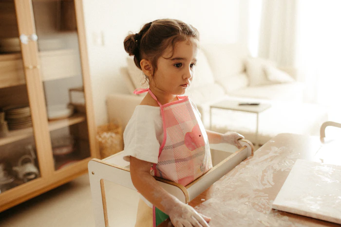 A young girl rolling out dough with flour