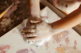 Child's hands covered in paint creating art.