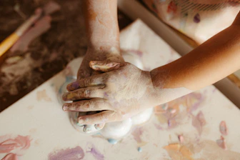 Child's hands covered in paint creating art.