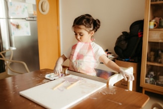 Young girl painting at a table with gloves on.