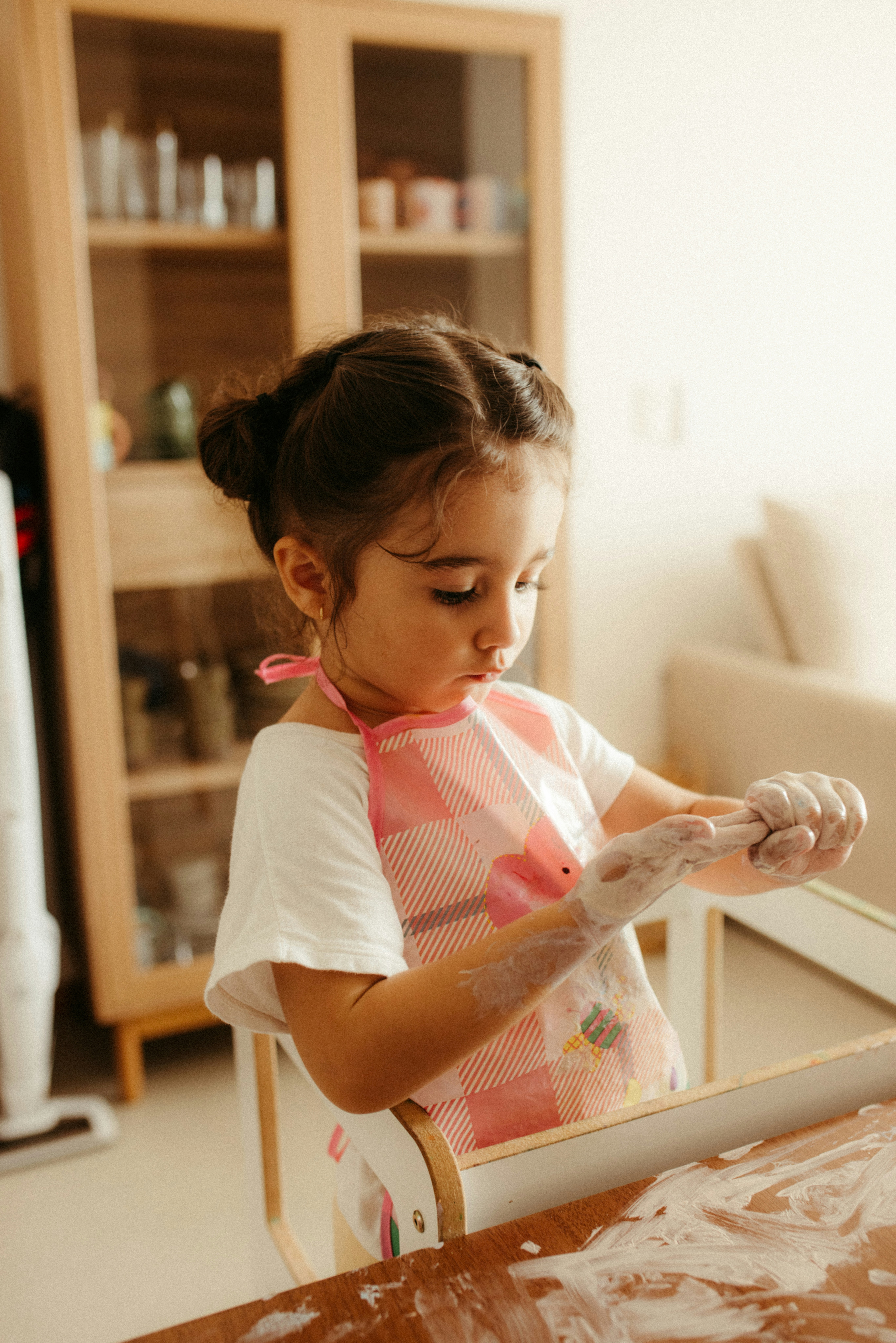 A young girl with hands covered in white powder.