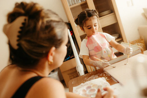 A mother watches her child making cookies