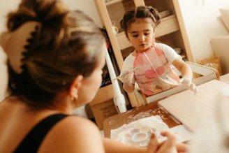 A woman watches a child playing with flour.