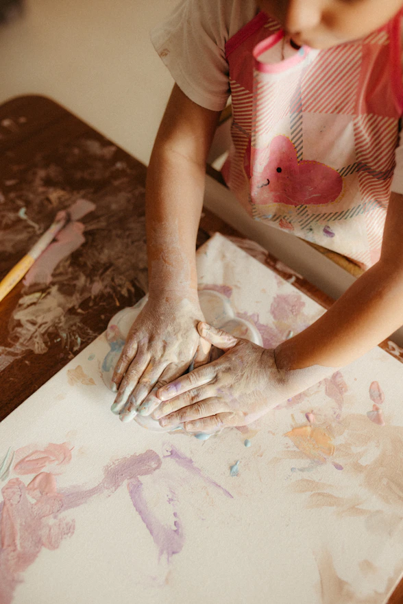 Child's hands covered in paint creating art